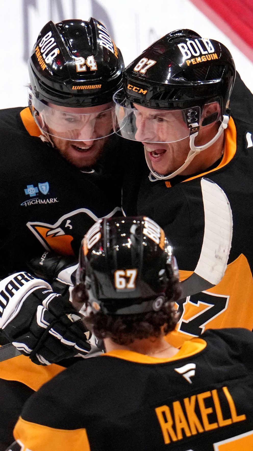 Ishockeyspelaren Rickard Rakell omfamnar lagkamrater i gula och svarta matchtröjor.