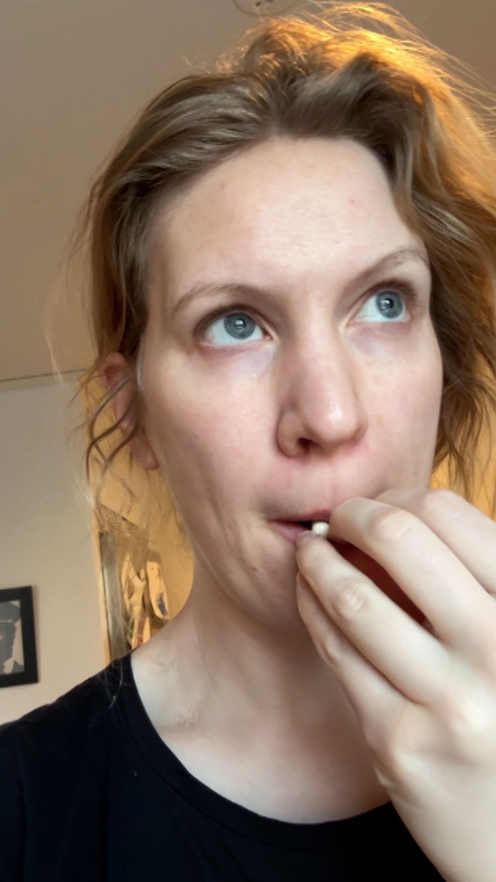 Person med uppsatt rött hår håller sin hand vid ansiktet mot neutral bakgrund.