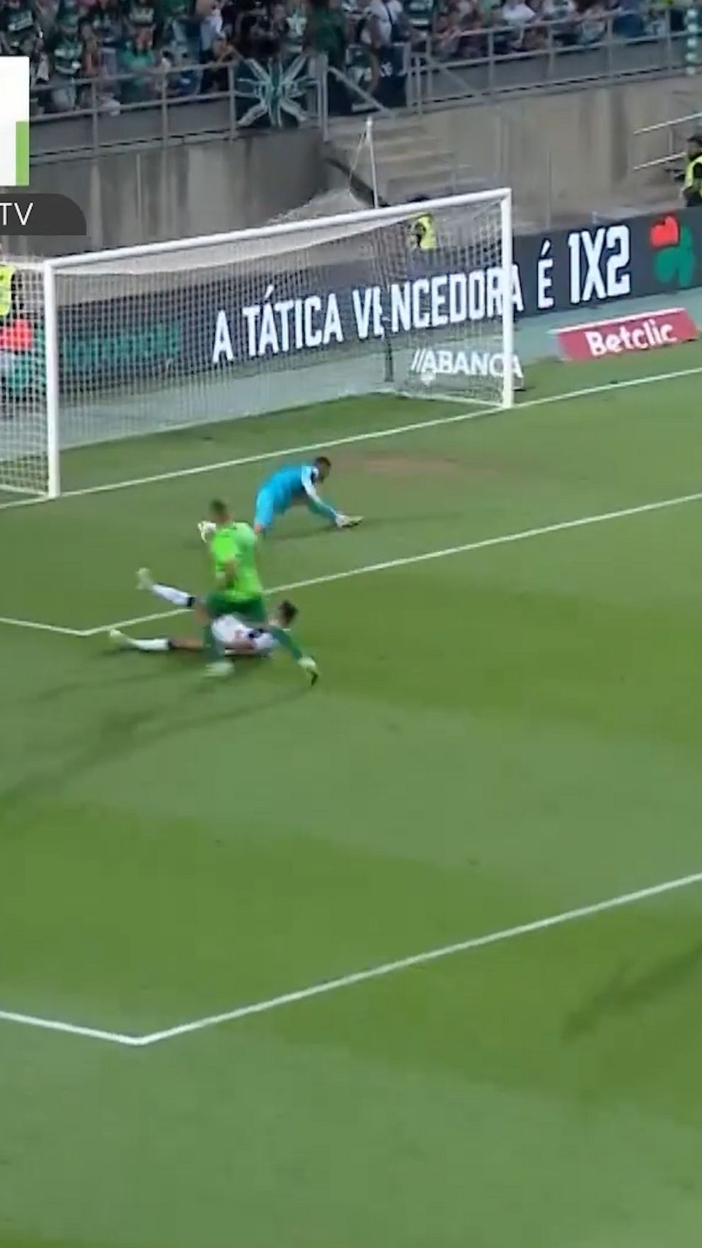 Fotbollsmålvakt räddar ett skott nära mållinjen, anfallare faller framför honom.