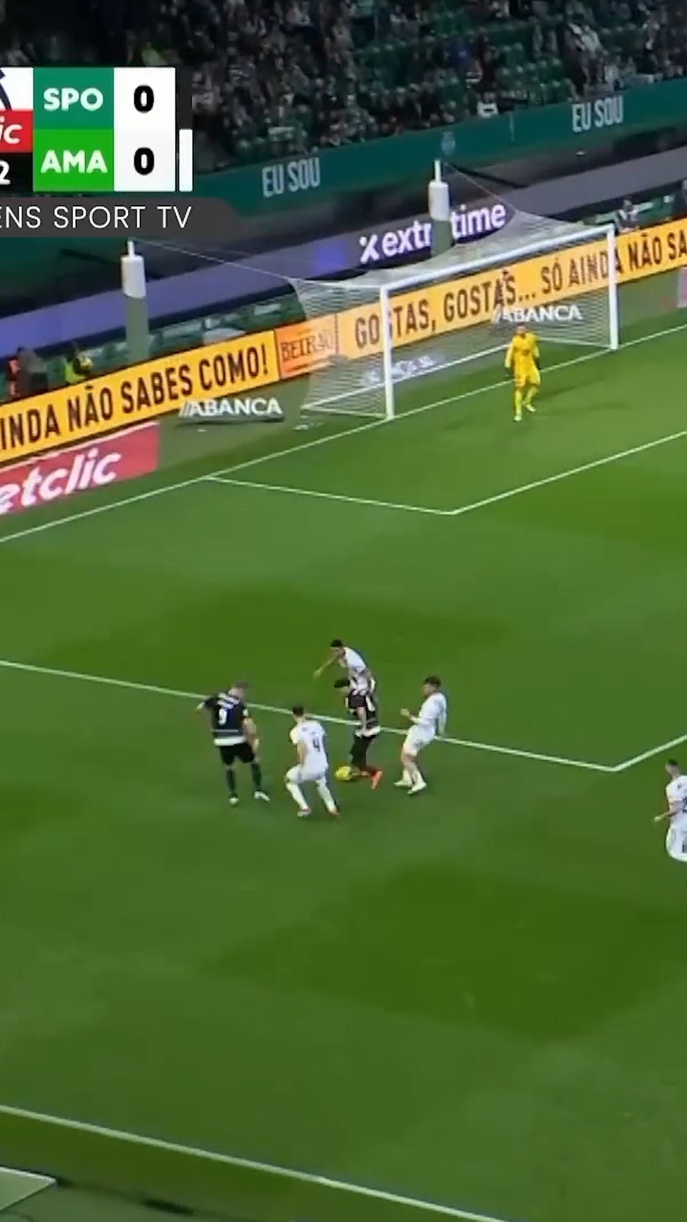 Fotbollsmatch, spelare nära mål försöker bryta sig loss från försvaret, målvakt redo.