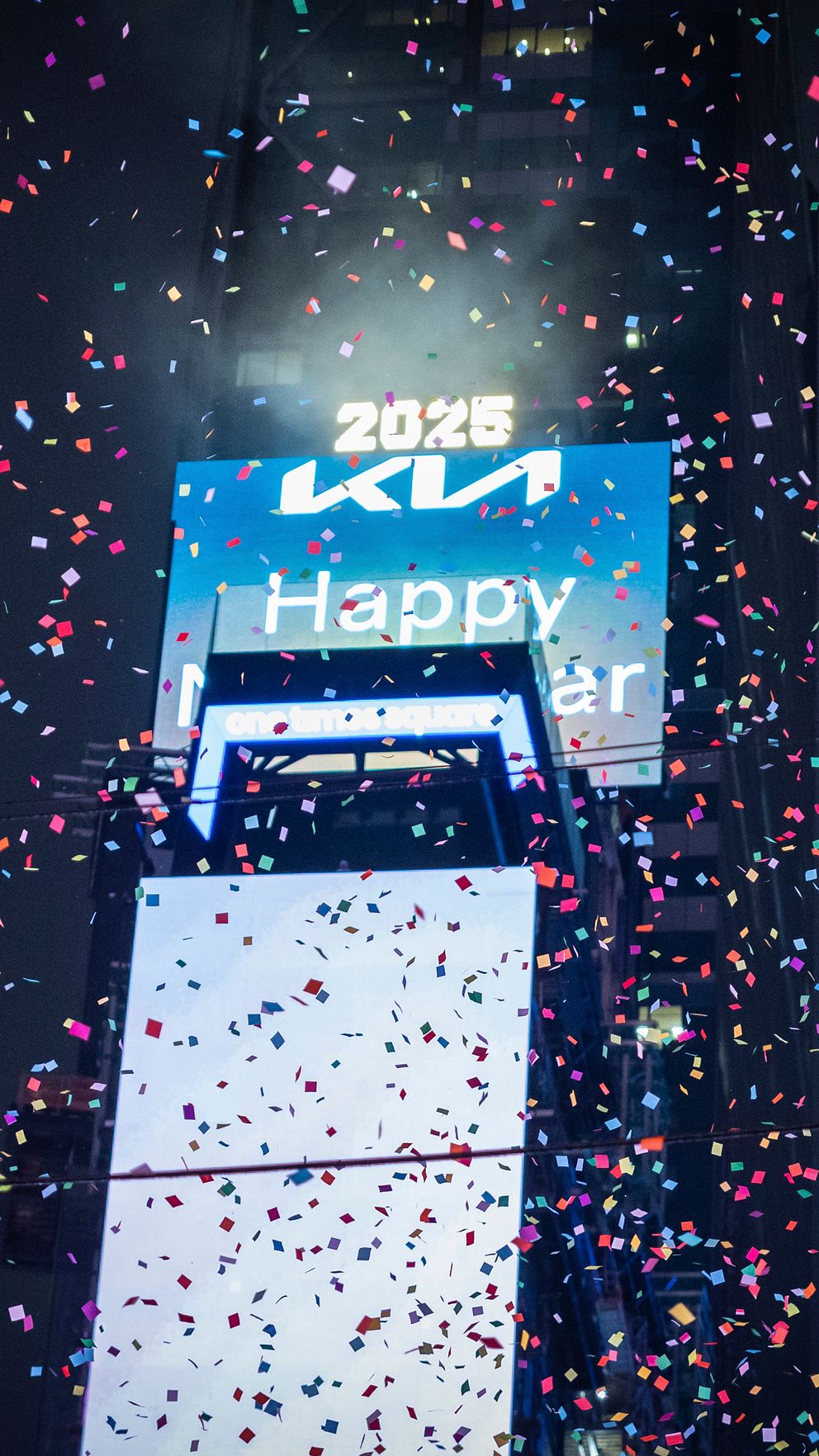 Färgglad konfetti faller över en stor skärm i Times Square som visar ”2025” och ”Happy New Year”, vilket firar det nya året.