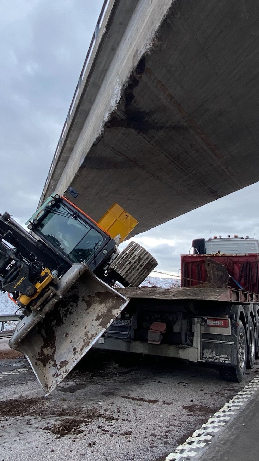 Lastbil med kran har kört in i bro på snöig motorväg.