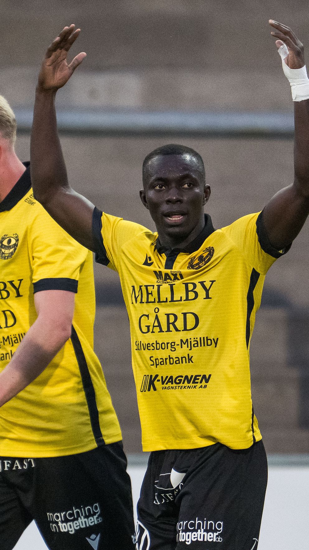 Fotbollsspelare i gula tröjor firar ett mål tillsammans på planen.