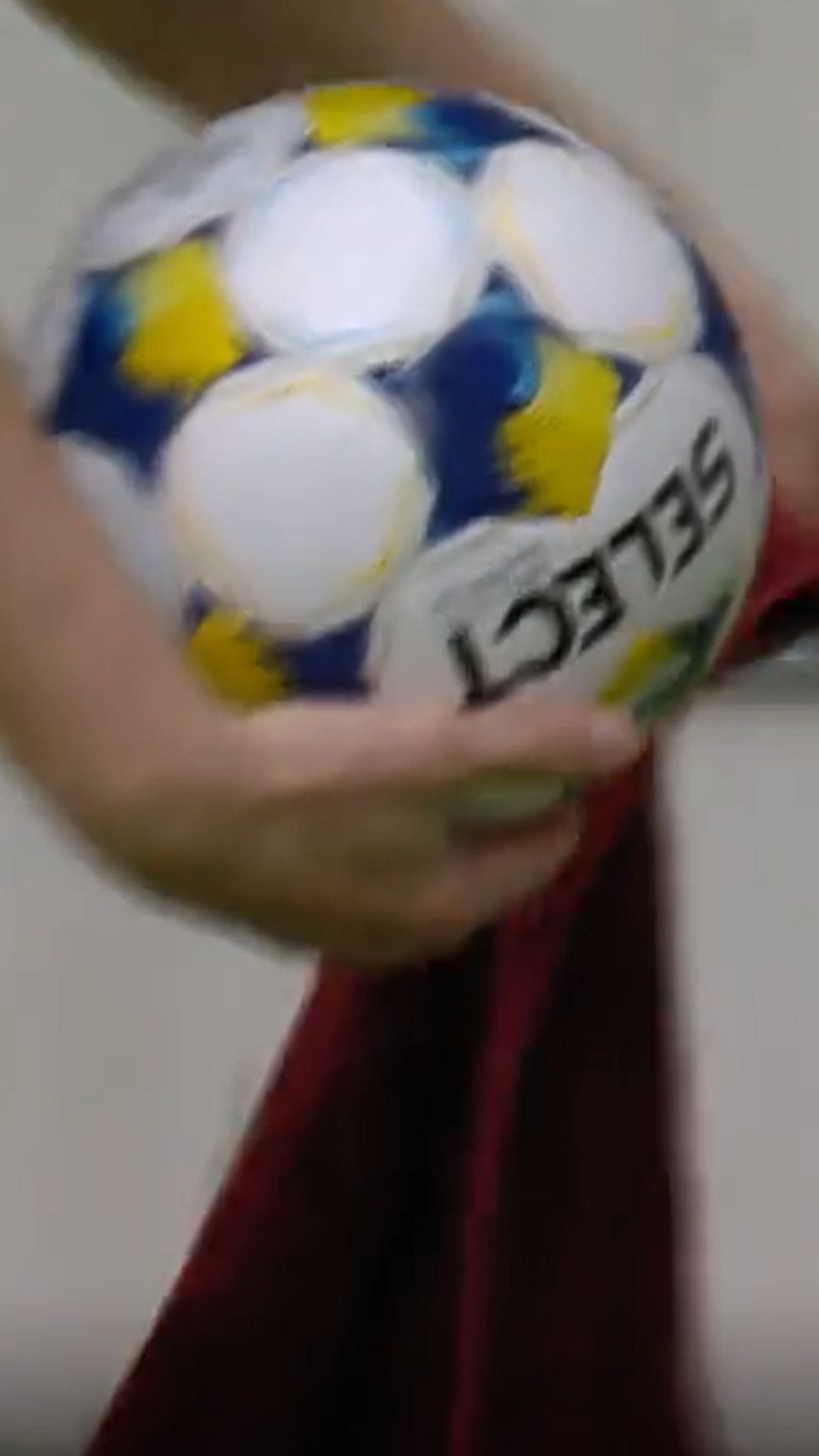 Person håller fotboll med en röd trasa över knät.