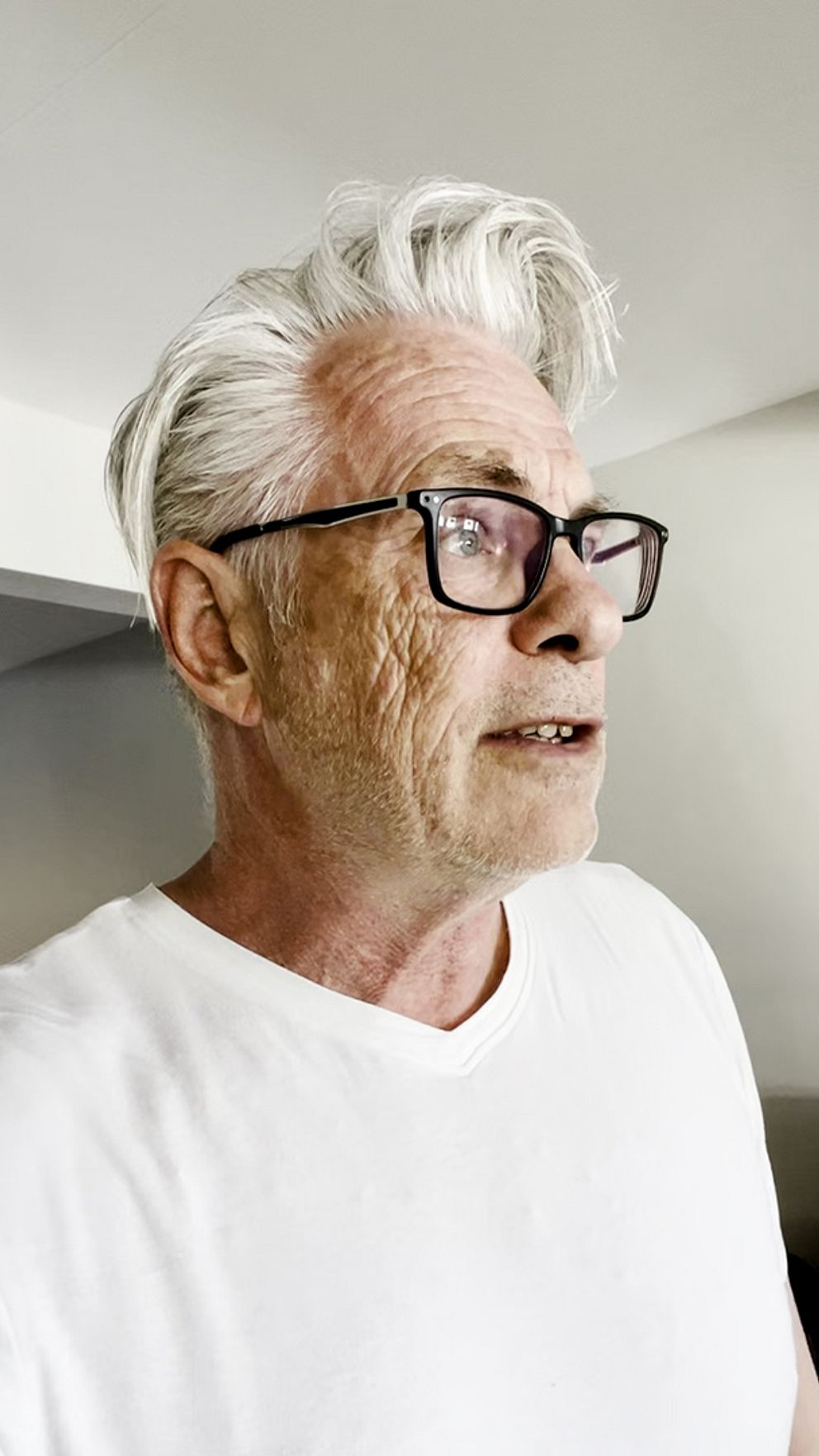 Person i vitt tröja framför en vågmönstrad röd bakgrund.
