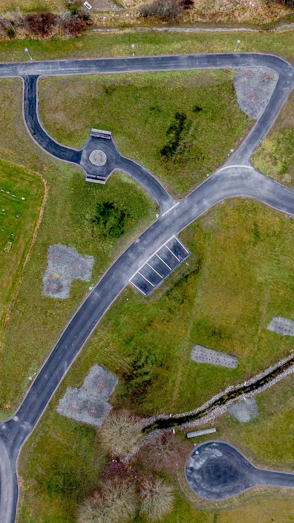 Flygbild över kyrkogård med gravstenar och gångstigar.