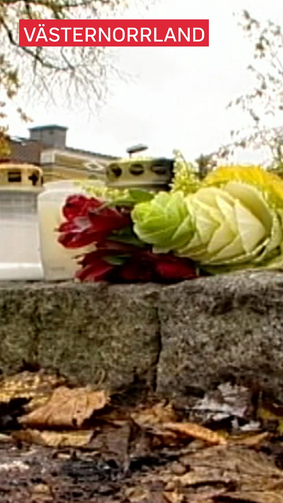 Blommor och ljus på stenmur.