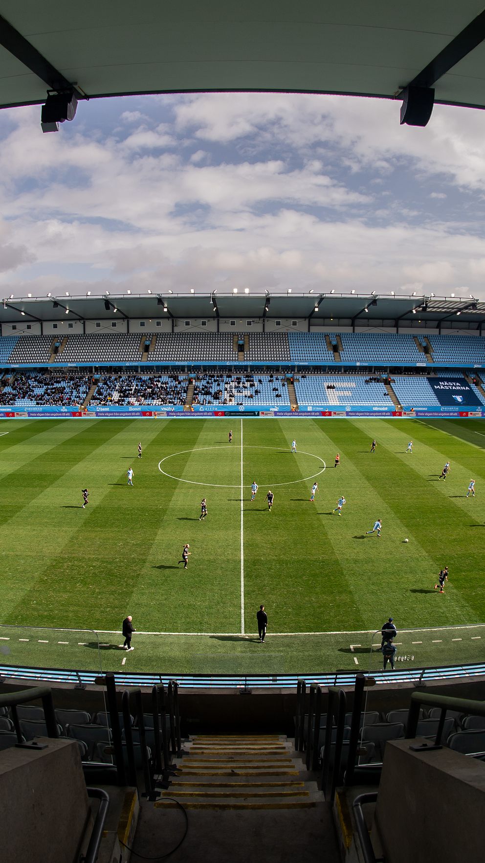 Tom fotbollsarena under en molnig himmel, sett från en hög läktarplats.