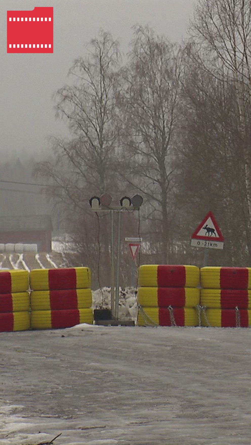Avspärrad väg med bommar och skyltar i vintermiljö. En bil närmar sig bommarna.