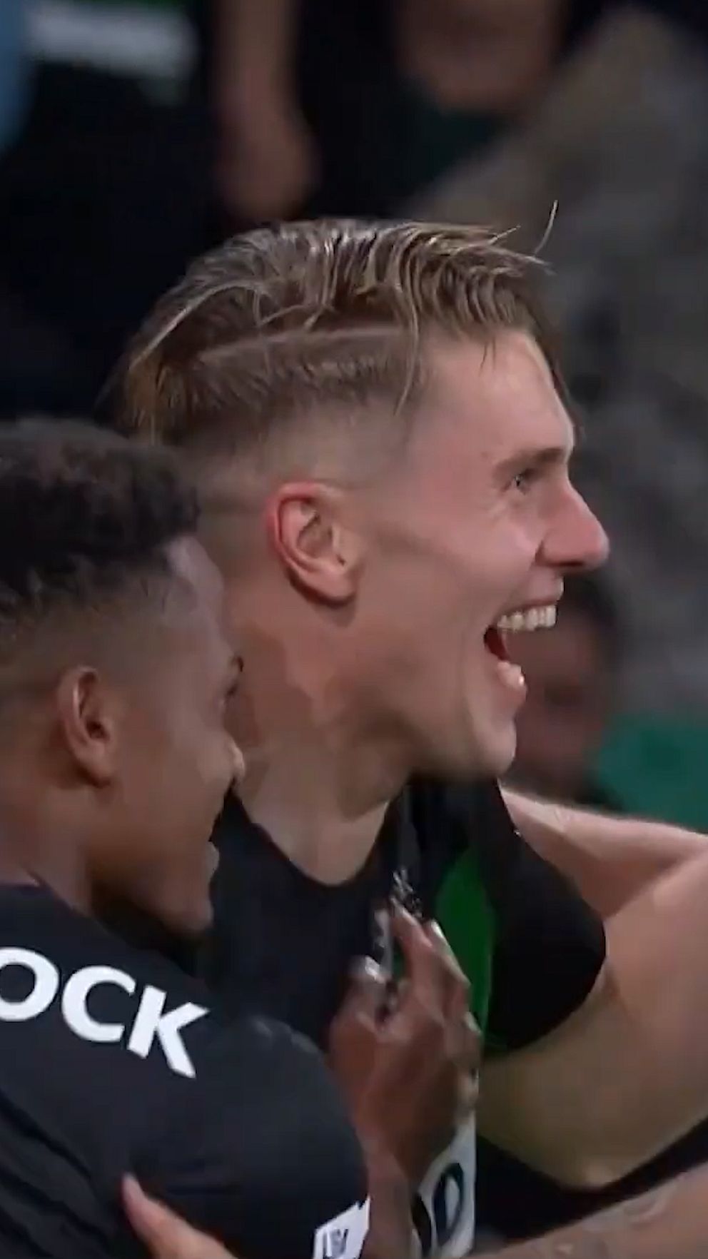 Två fotbollsspelare firar tillsammans efter ett mål på planen.