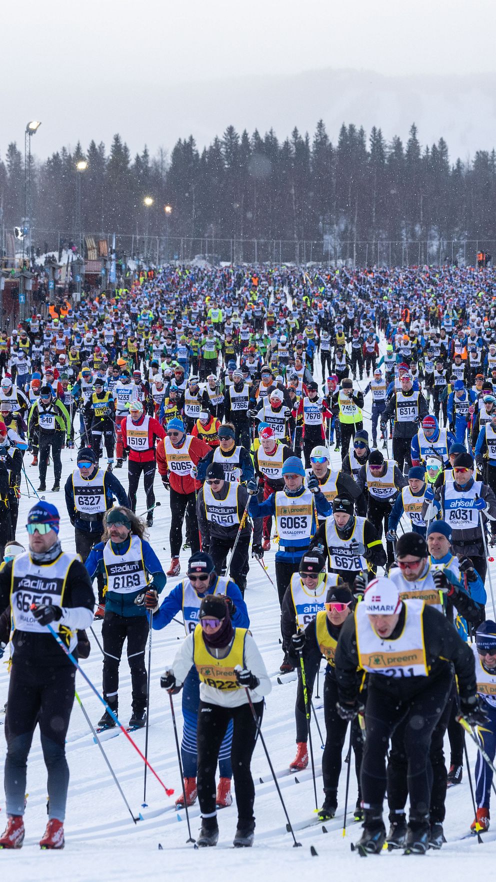 Deltagare vid starten av ett långlopp på skidor, tätt samlade på snötäckt mark.