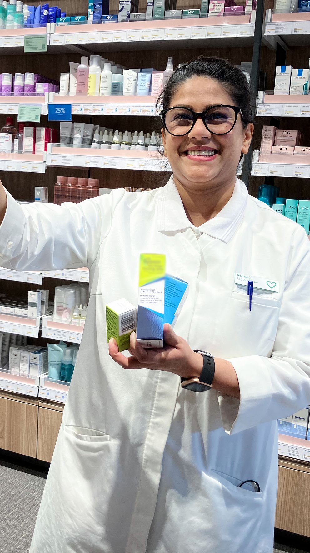 Apotekspersonal sorterar medicinförpackningar på hyllor i ett apotek.