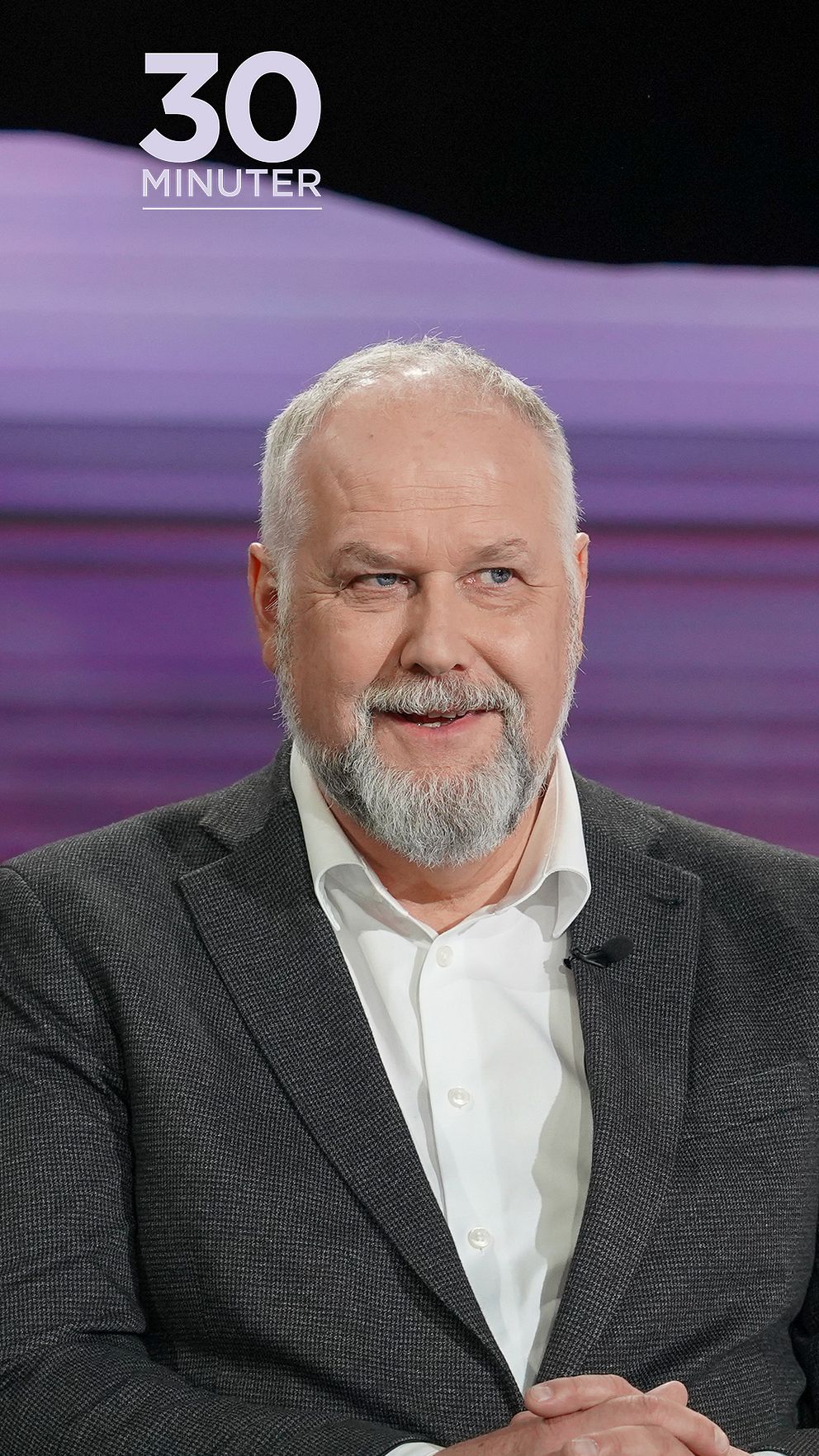Jonas Sjöstedt (V) i grå kavaj sitter mot en lila bakgrund. Texten ”30 MINUTER” syns högst upp.