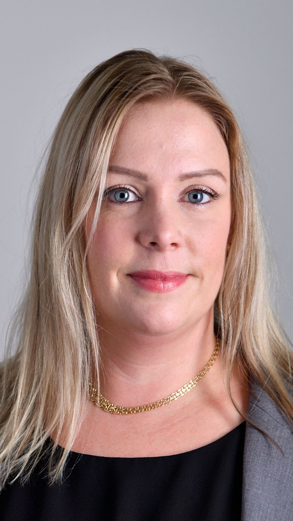 Kvinna, Angelica Lundberg (SD) med ljust långt hår, klädd i kavaj, tittar in i kameran.