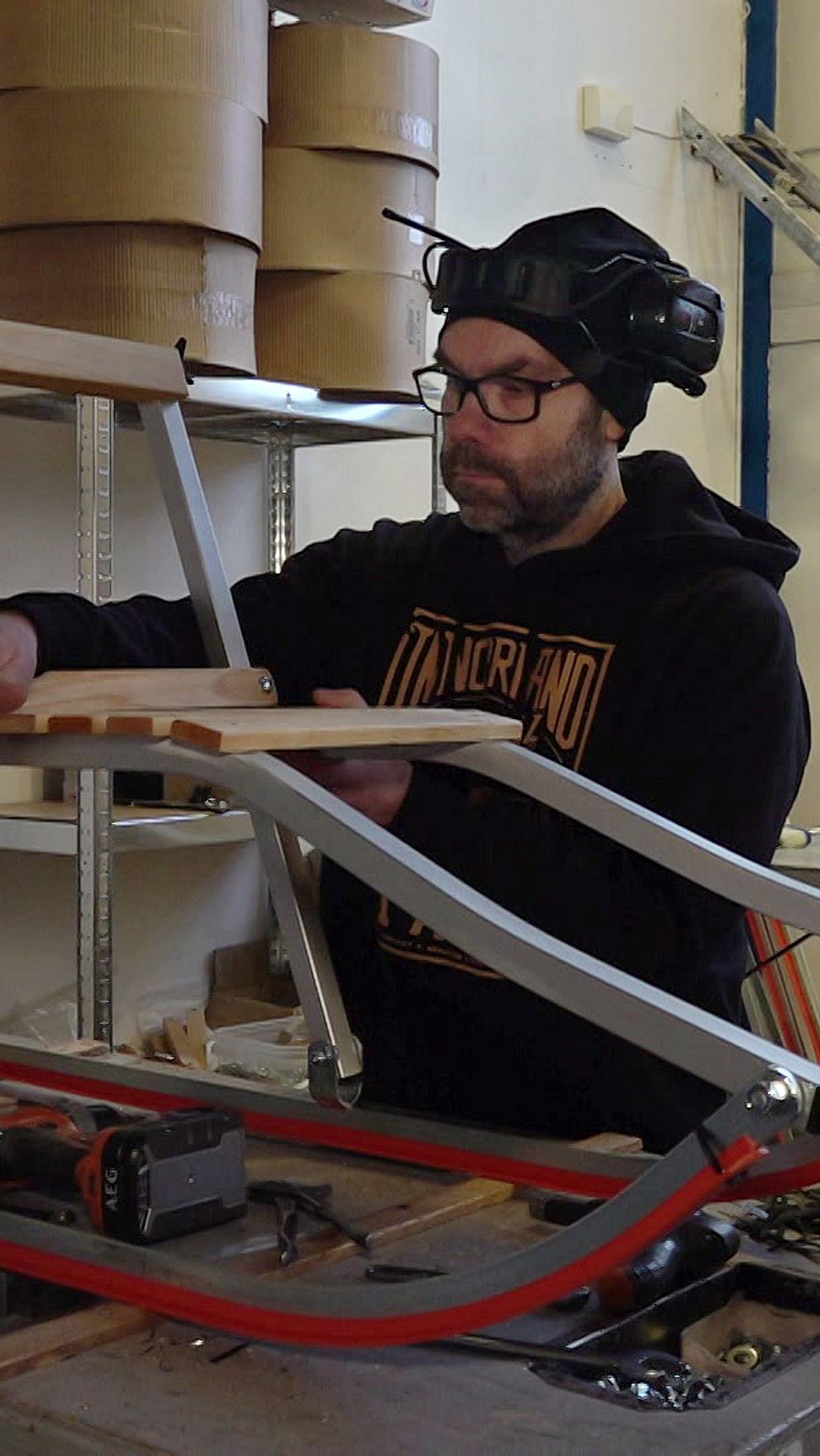 Mikael Eklund – en man i svart hoodie, mössa och med hörselkåpor på huvudet, arbetar med en spark i sparkfabriken i Brunflo