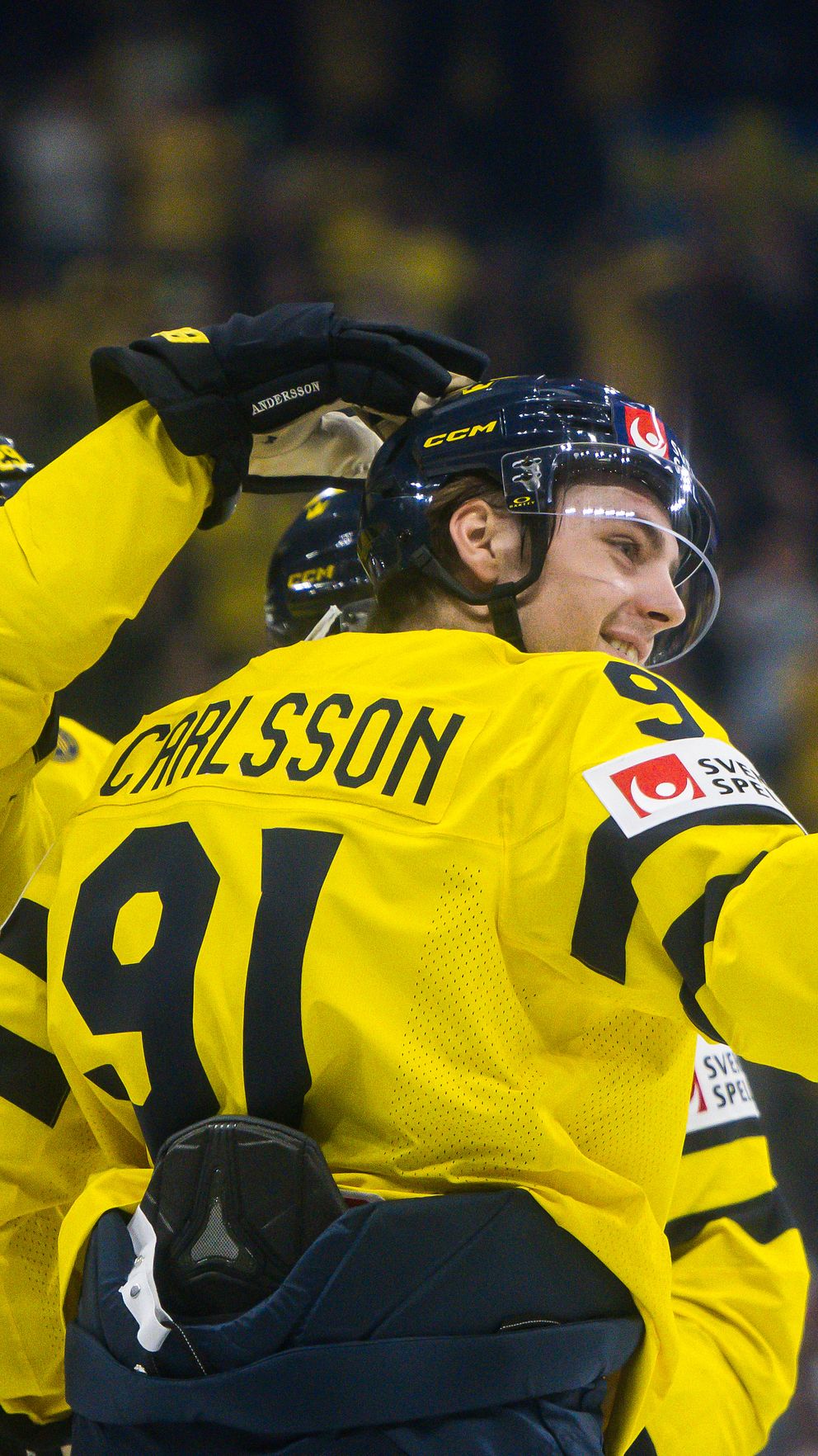 Ishockeyspelare i gula tröjor firar ett mål tillsammans på isen.