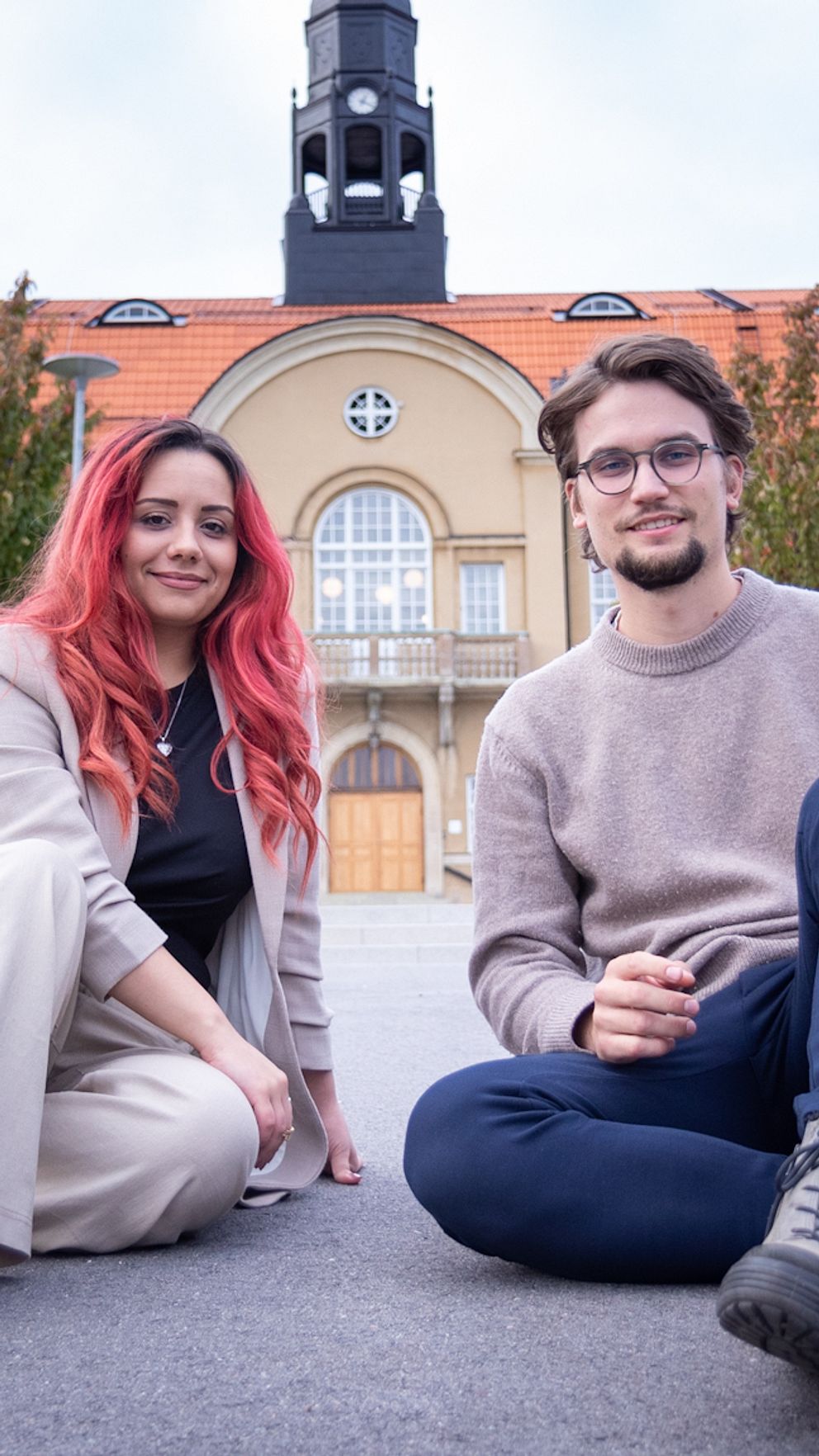 Två reportrar sitter framför Staffangymnasiet i Söderhamn.