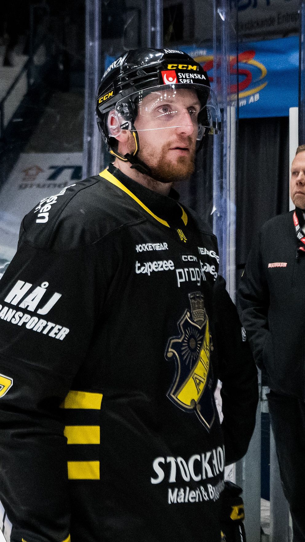 Ishockeyspelare i svarta matchkläder lämnar isen efter slutsignal, publik i bakgrunden.