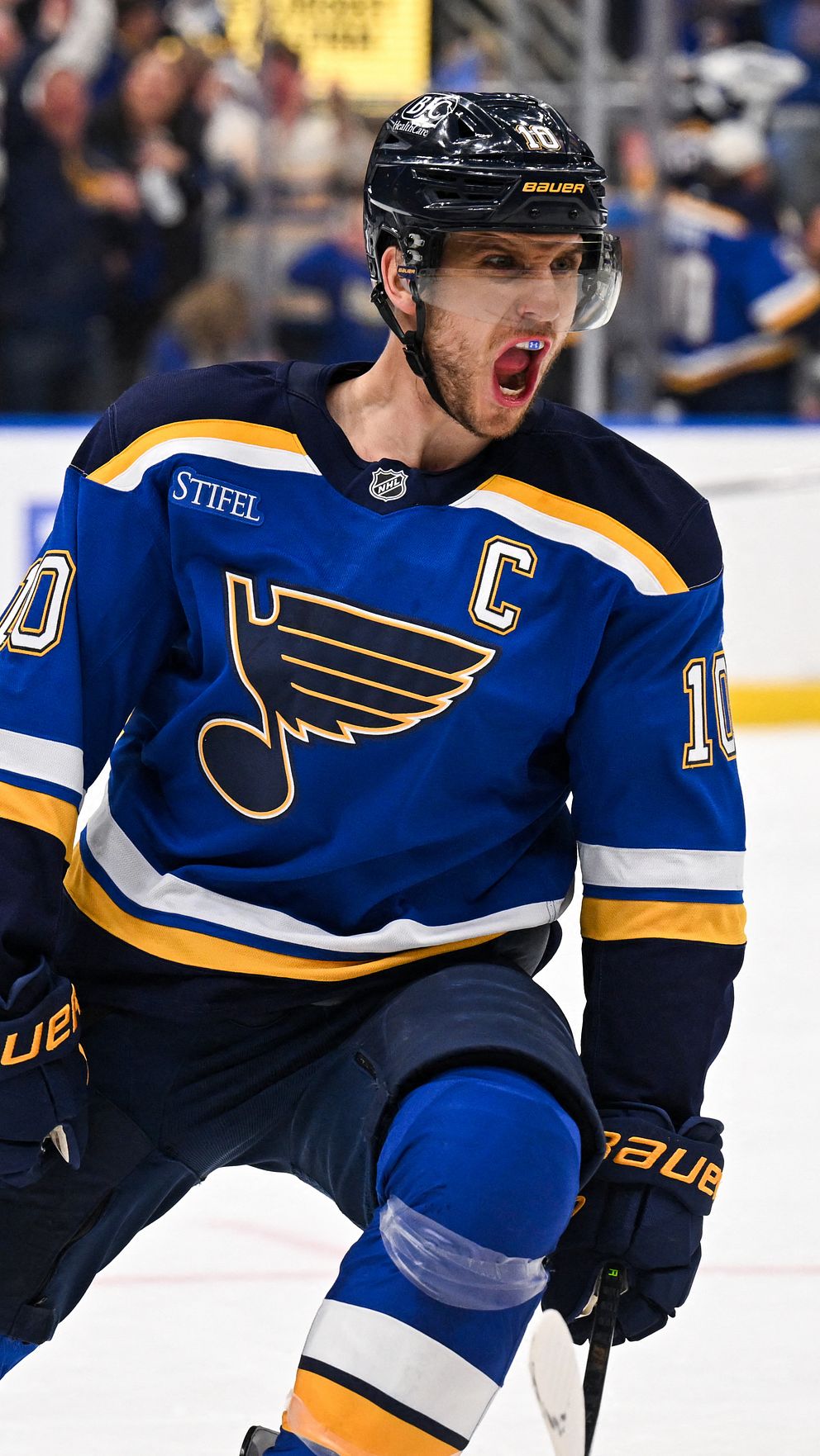 Ishockeyspelare i blå St. Louis Blues-tröja värmer upp inför match, publik i bakgrunden.