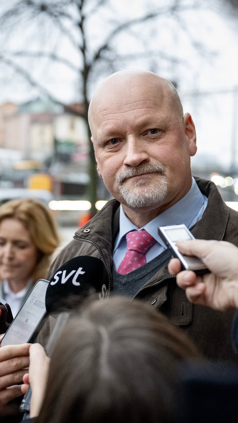 Person intervjuas av journalister på en stadsgata, mikrofon med SVT-logga syns.