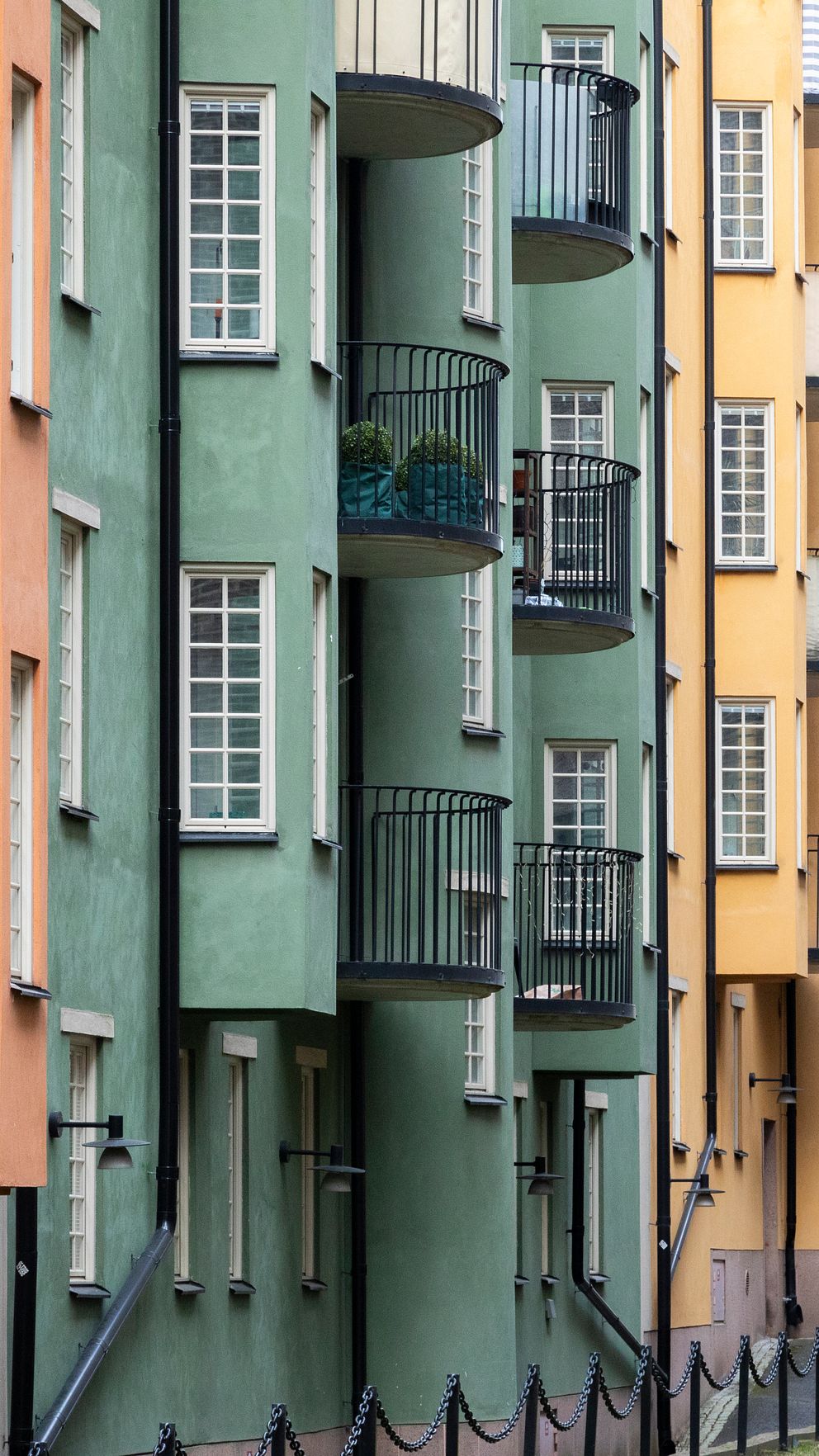 Flerfärgade bostadshus i rad med balkonger och stora fönster.