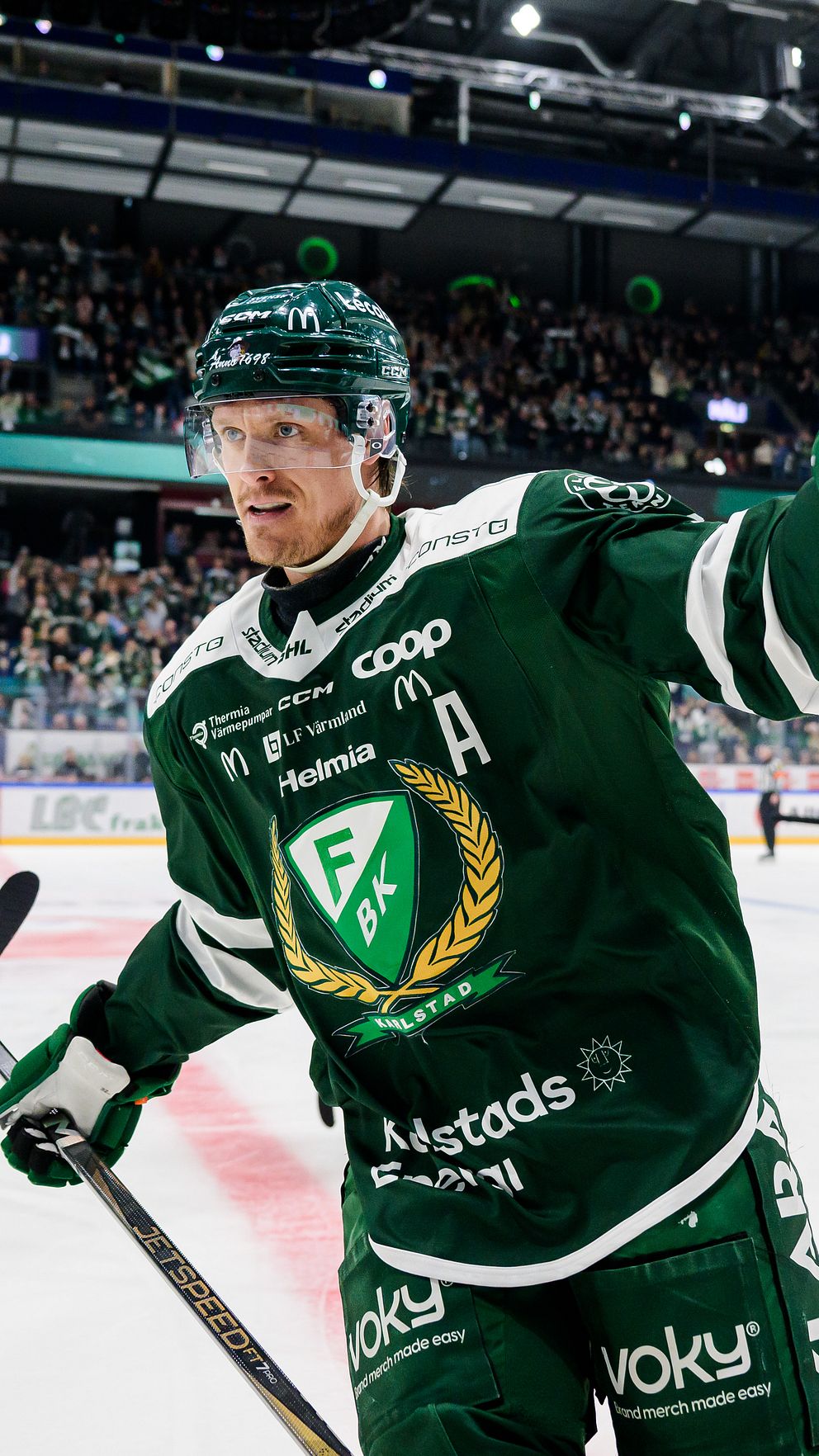 Hockeyspelare i gröna dräkter firar mål på isen inför en fullsatt arena.