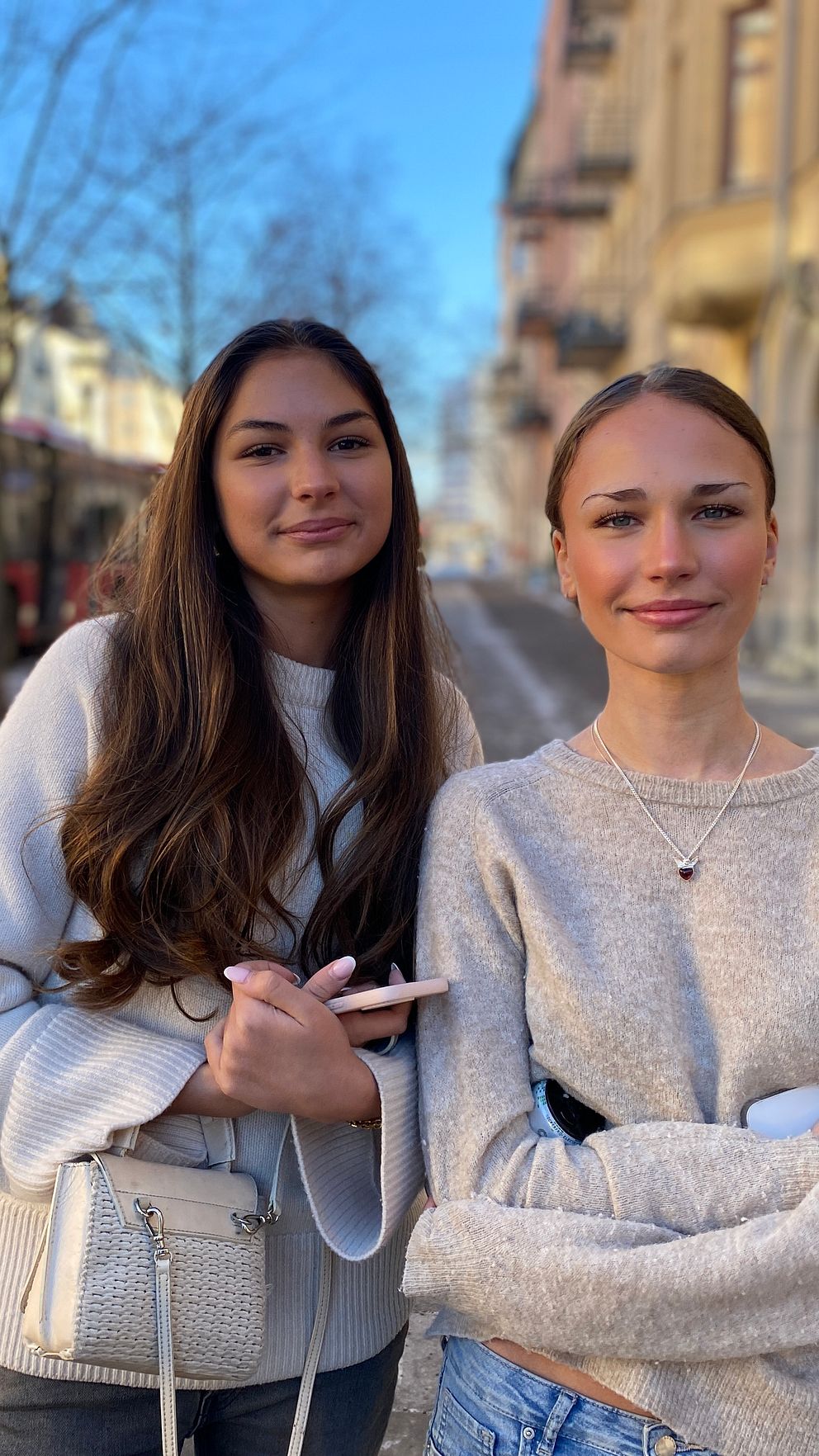 Två personer står på en vintergata med en röd buss i bakgrunden.
