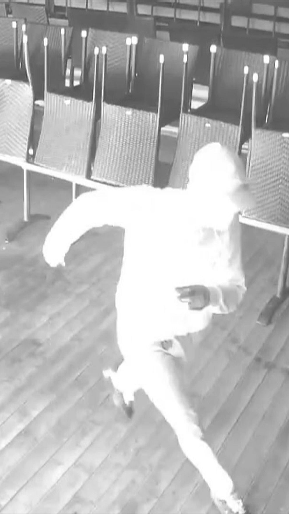 Gärningsperson syns i svart-vitt från en övervakningskamera när hen springer över Rådhusets uteservering efter att ha antänt byggnaden i Falun.