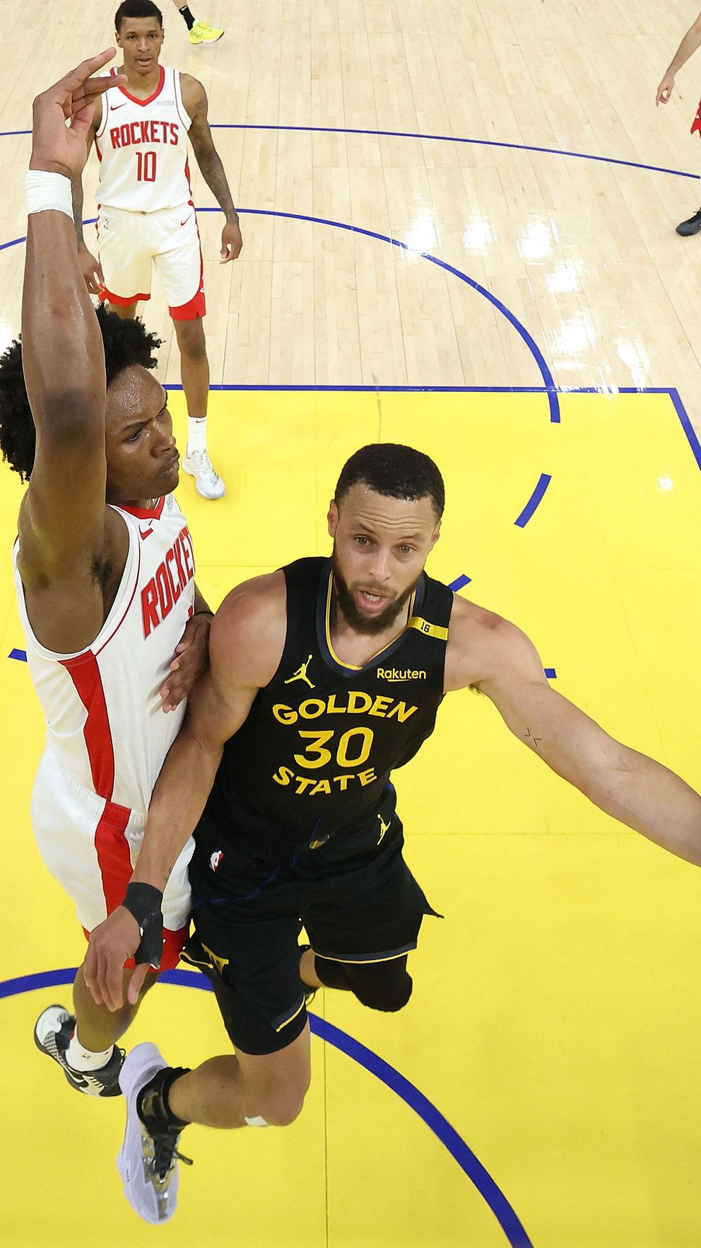 Stephen Curry gör ett upphopp under försvar från en Miami Heat-spelare nära korgen.