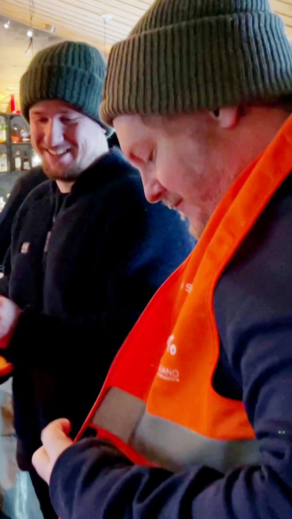 Två personer som står i en bar och har reflexvästar på sig.