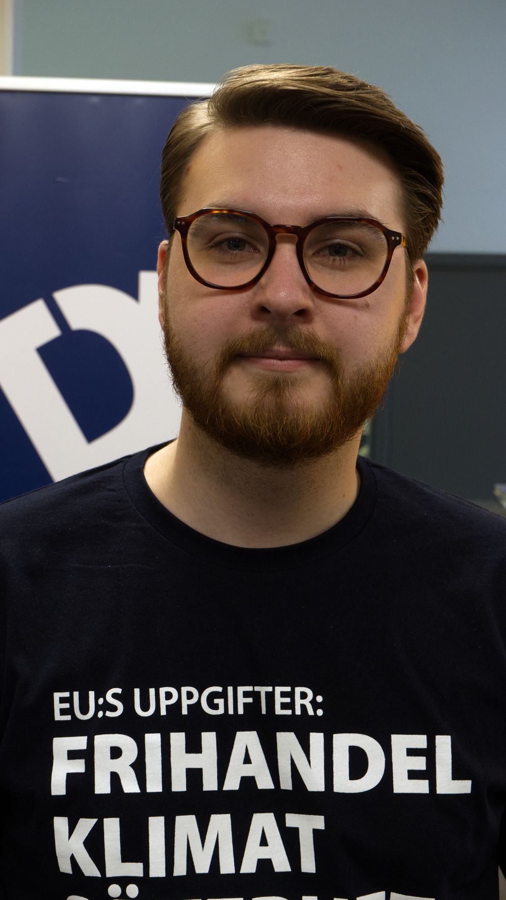 Ung man i glasögon och skägg tittar in i kameran
