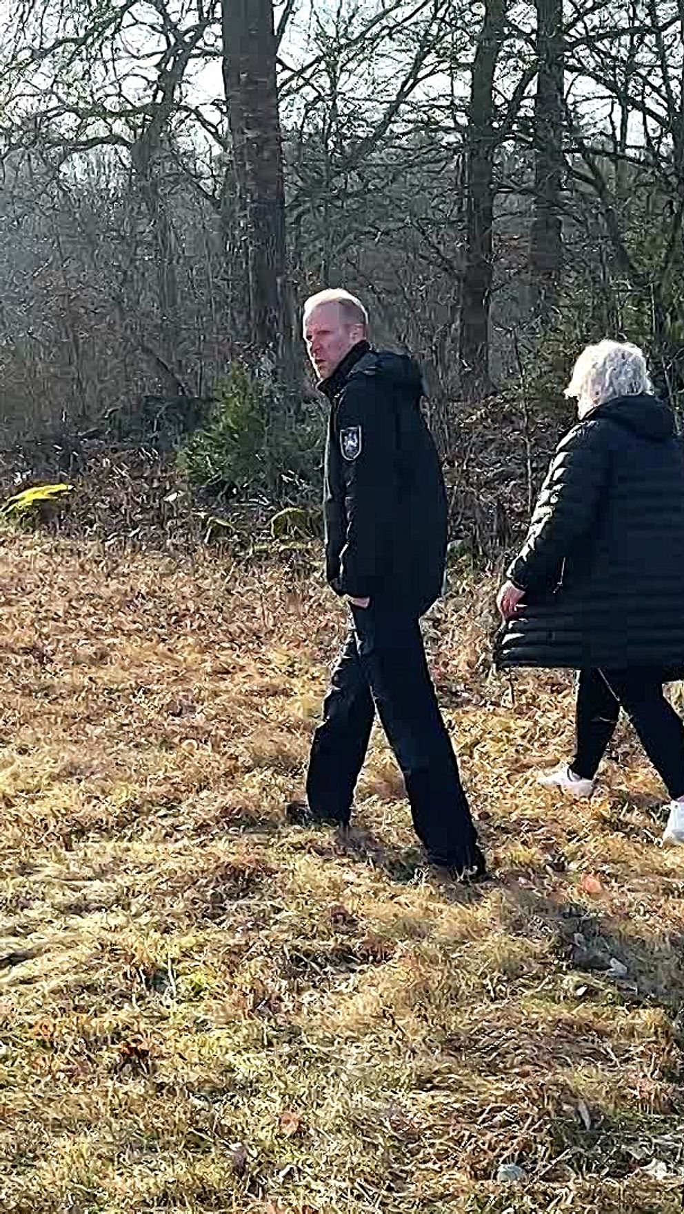 Två personer promenerar genom en höstlik skogsdunge.