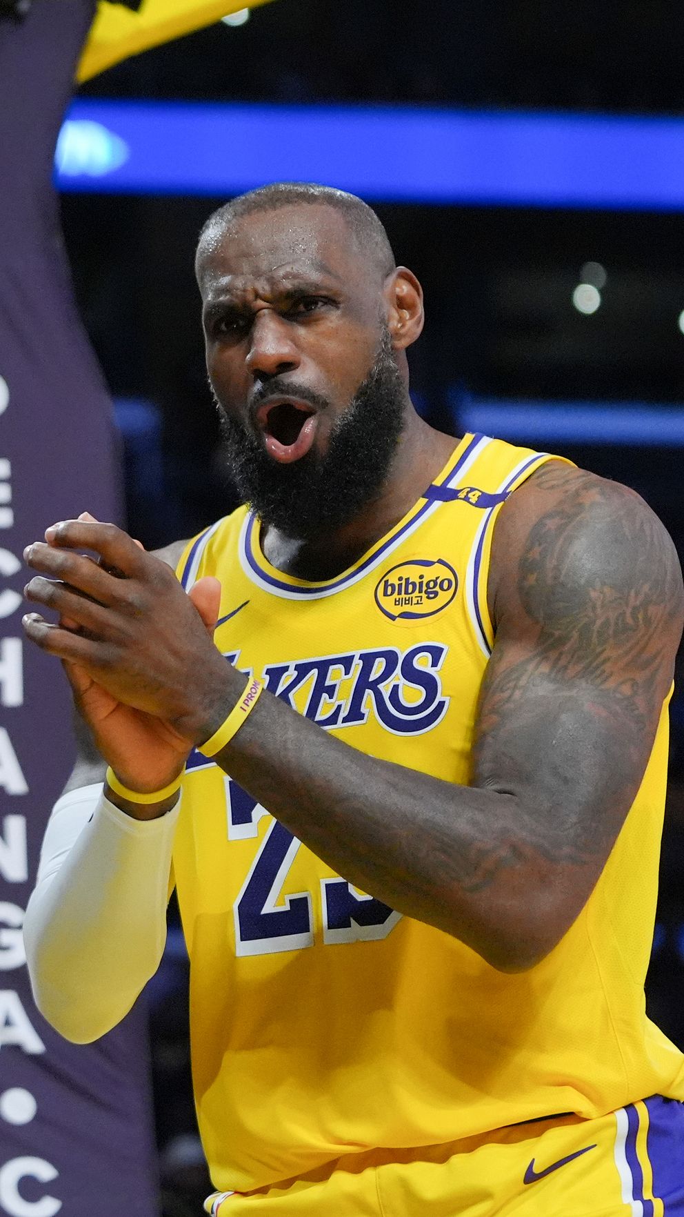 Basketspelare i Lakers-uniform applåderar på arenan.