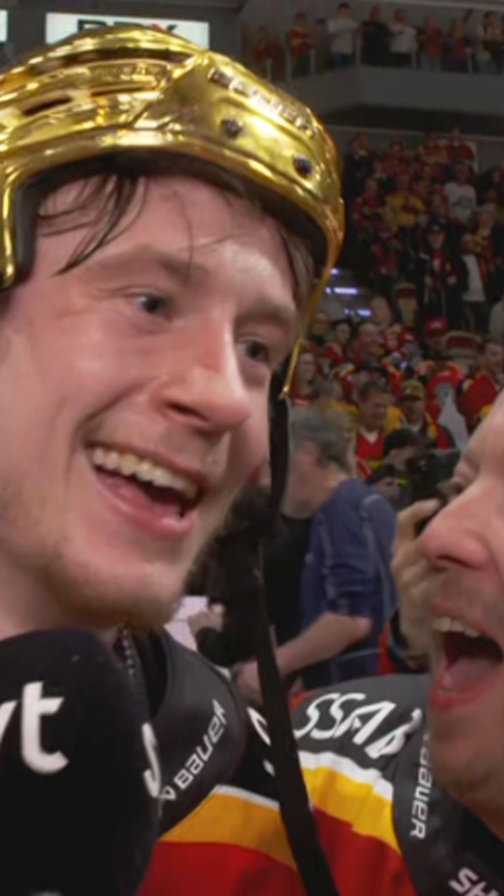 Ishockeyspelare med guldfärgad hjälm intervjuas av SVT efter match inför publik.