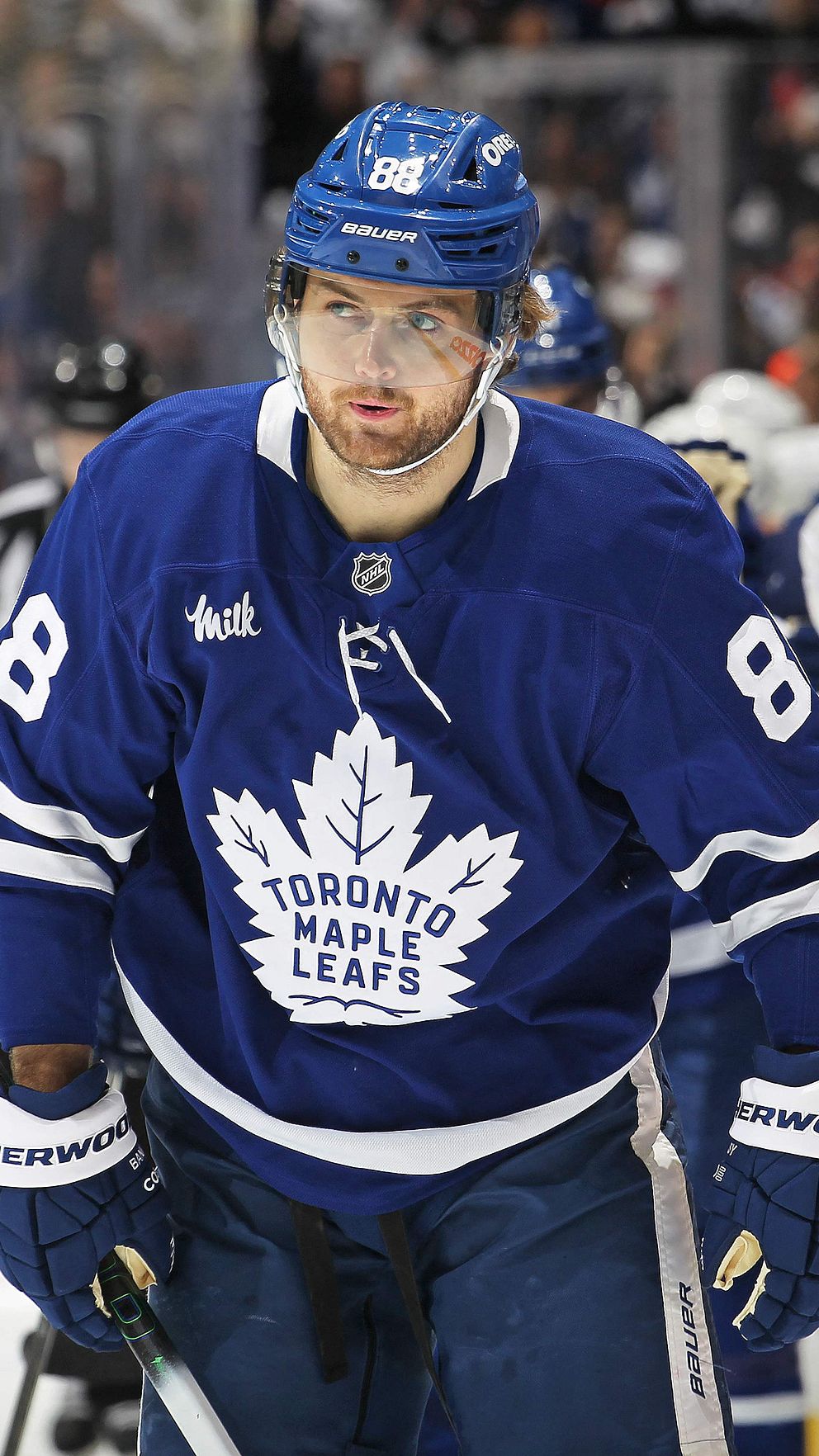 Två ishockeyspelare i Toronto Maple Leafs tröjor på isen under match.