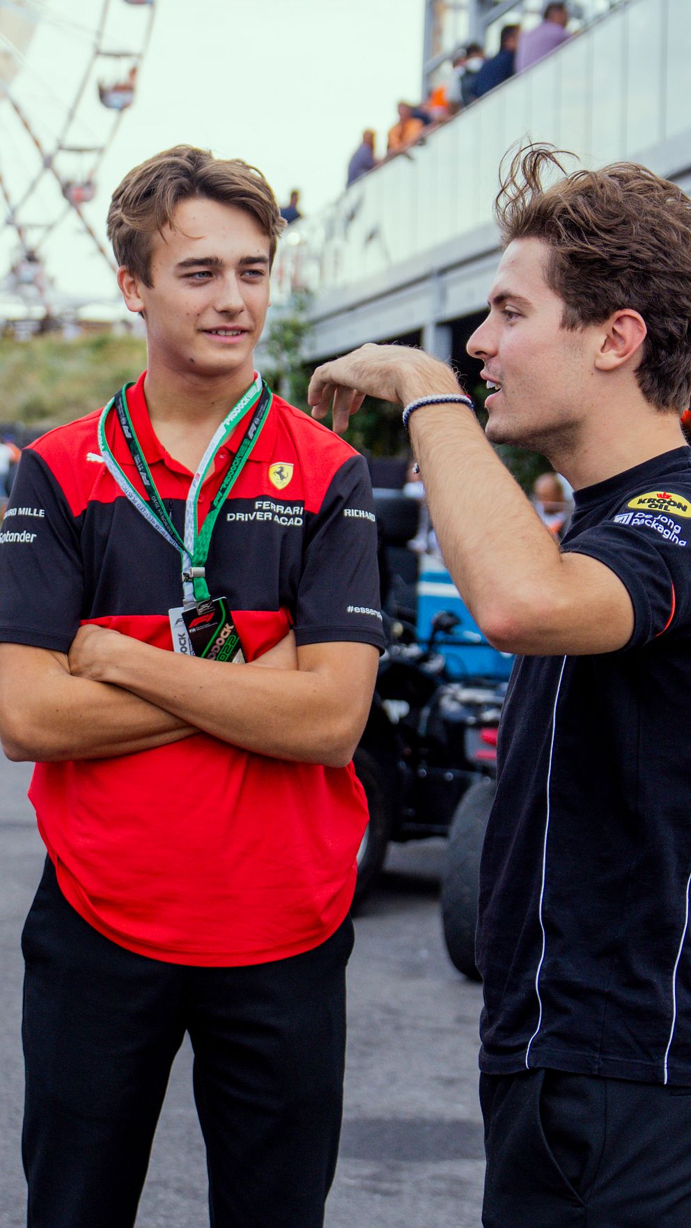Tre personer samtalar i depån vid ett motorsportevenemang. En person bär officiell teamklädsel.