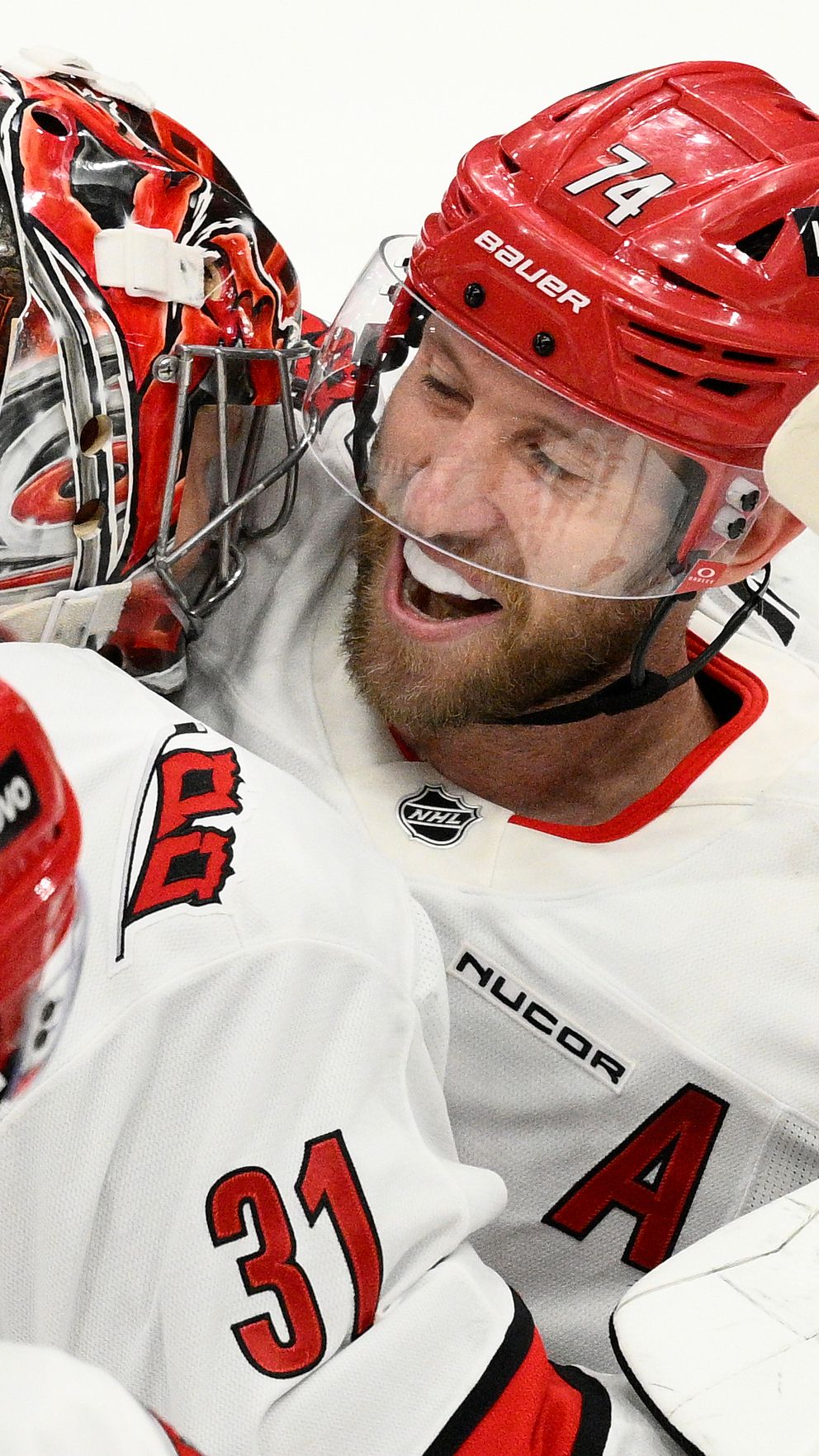 Ishockeyspelare i rödvita matchställ kramar om varandra och firar på isen.