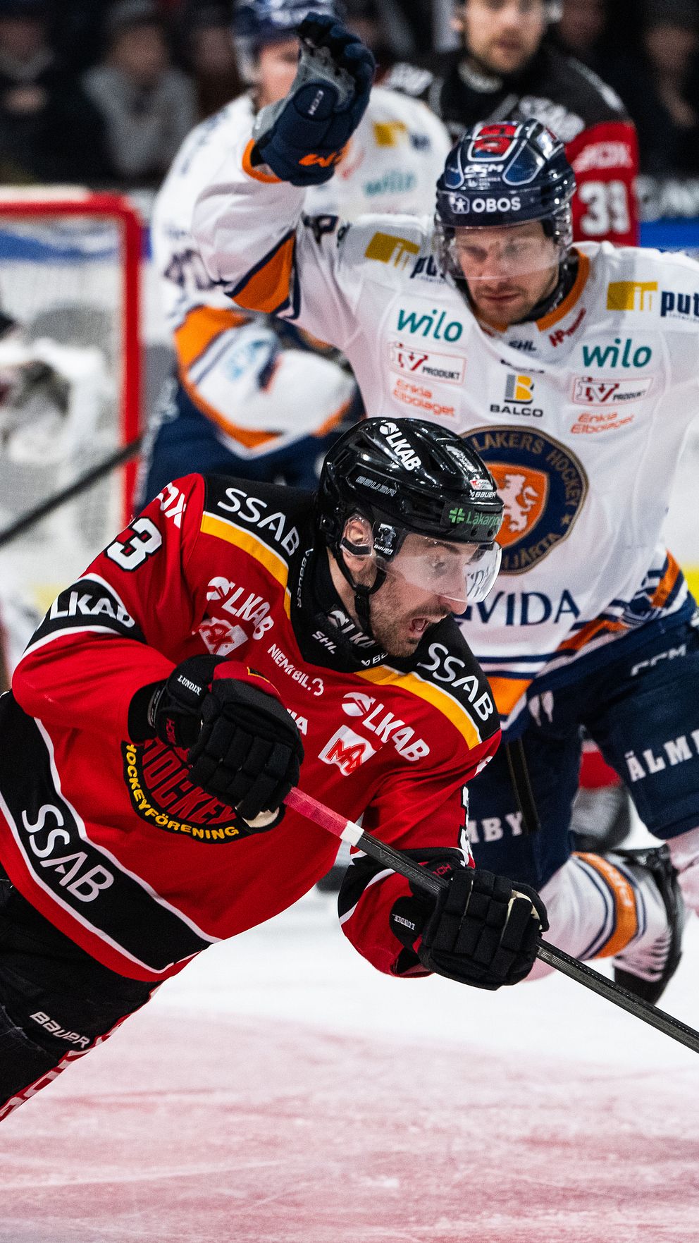 Ishockeyspelare kämpar om pucken framför målvakten under en match.