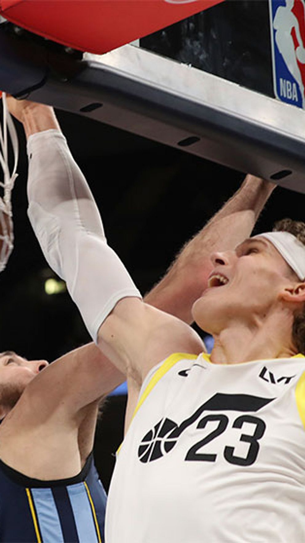 Basketspelare i kamp under korgen, den ena försöker blockera den andres skott.