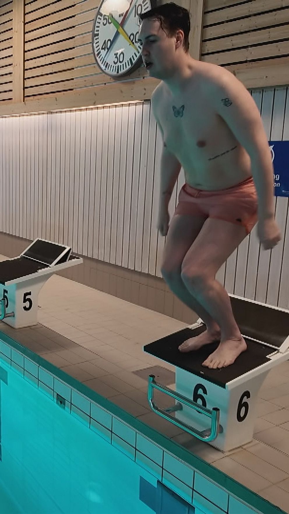 Christoffer Johansson förbereder hopp från startblock vid en simbassäng.