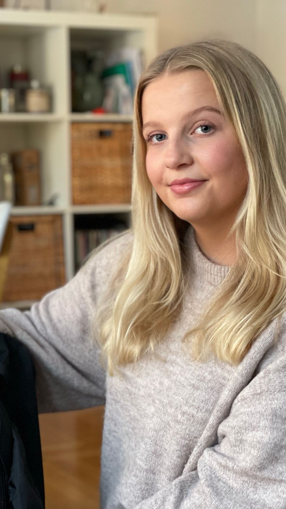 Kvinna med långt, blond hår sitter i ett rum, håller en ryggsäck med flaggor.