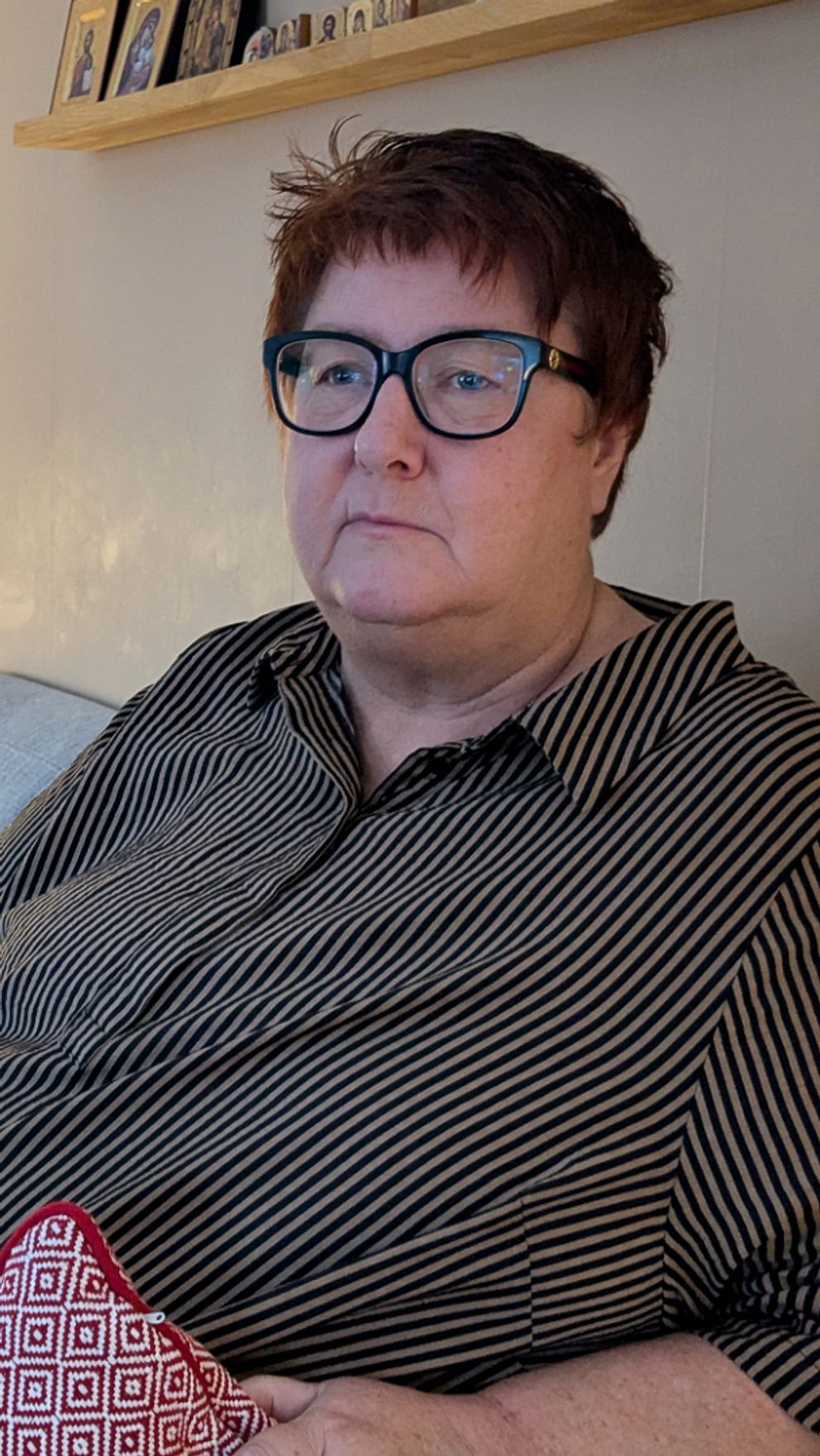 Cathrine sitter i en grå soffa i ett vardagsrum. I bakgrunden lyser en lampa på ett fyrkantigt soffbord.