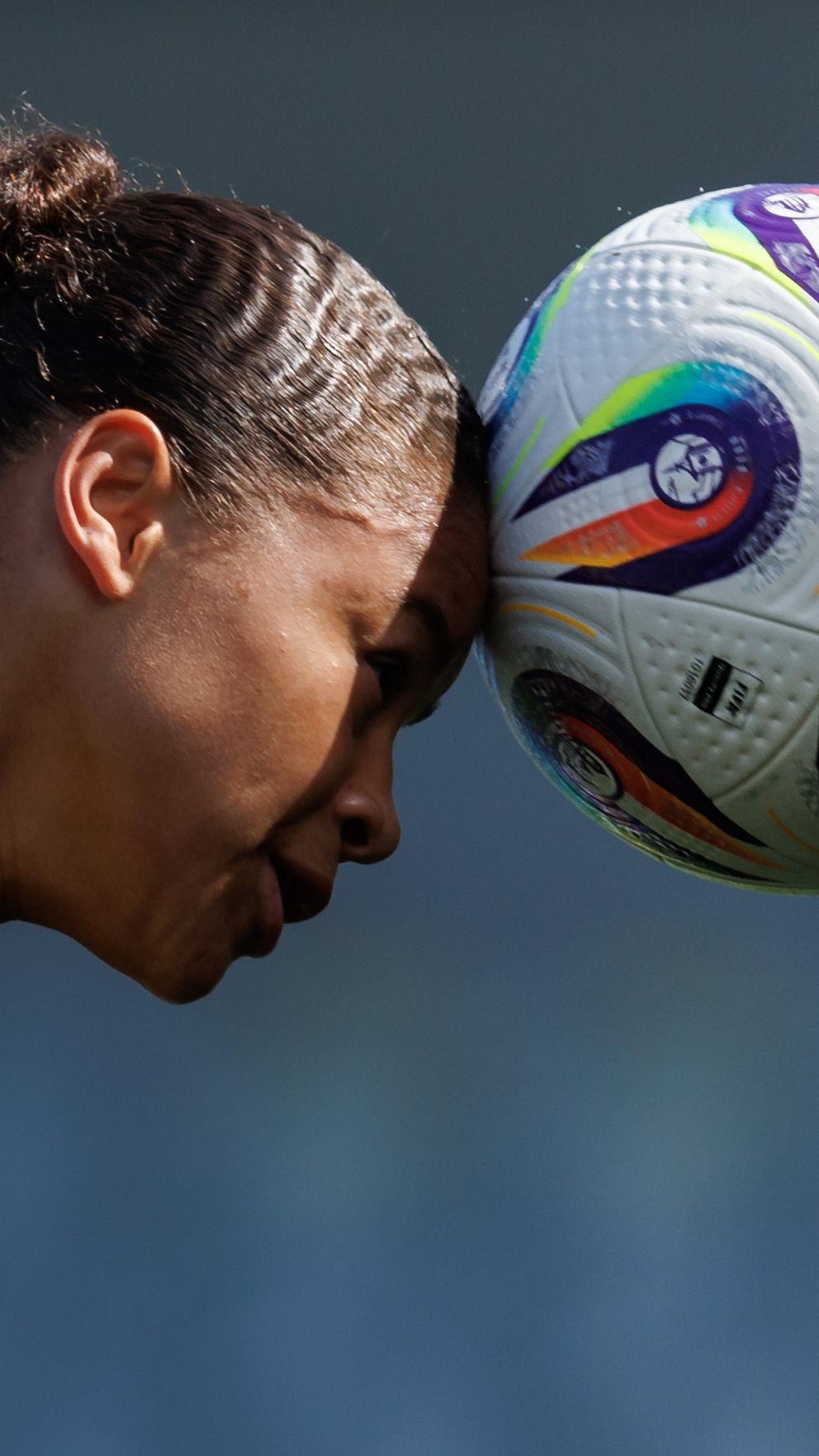 Fotbollsspelare i gulsvart tröja nickar en boll under en match.