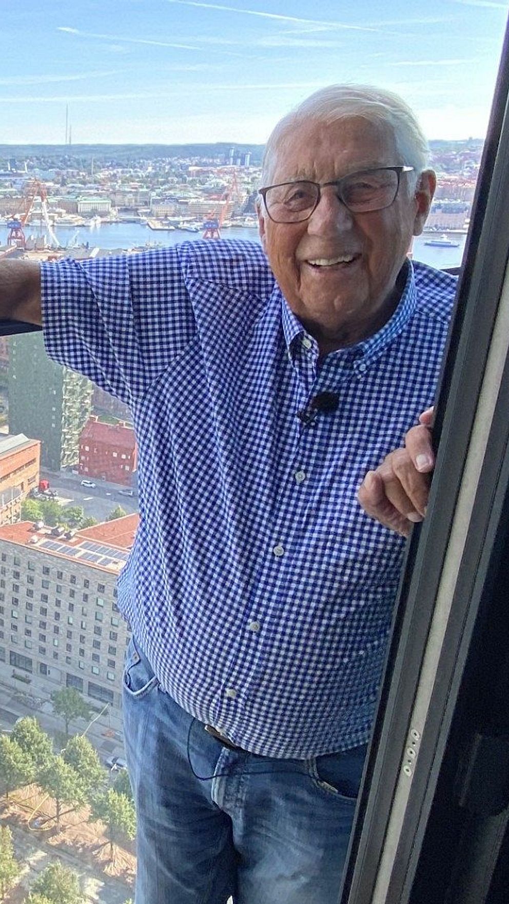 Evan Hellström, 91,  står på sin balkong och lutar sig skrattande mot glasräcket på 29:e våningen i Nordens högsta byggnad, Karlatornet i Göteborg.