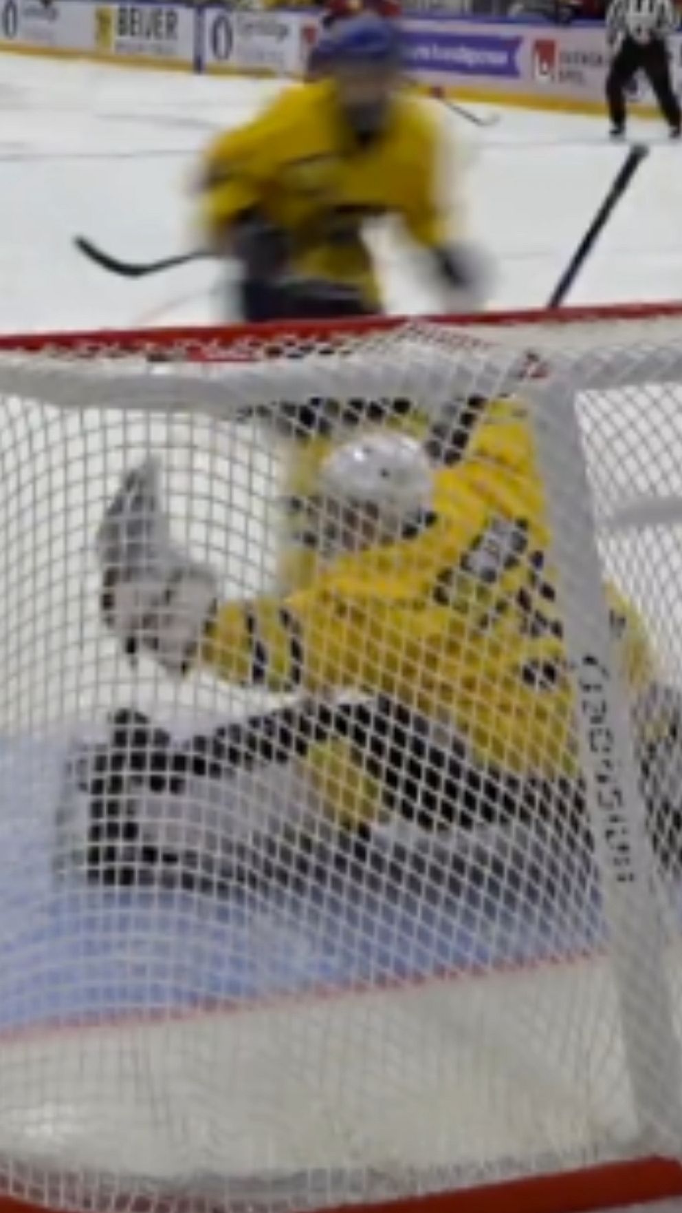 En delad bild som visar en spännande hockeysekvens. Till vänster försöker en spelare i röd tröja skjuta pucken förbi en målvakt i gul tröja, som ligger på knä för att blockera skottet. Till höger fångas målvakten i en dramatisk räddning där han sträcker ut sig för att fånga pucken med sin handske. Bakgrunden visar en ishockeyrink med reklamskyltar och åskådare.