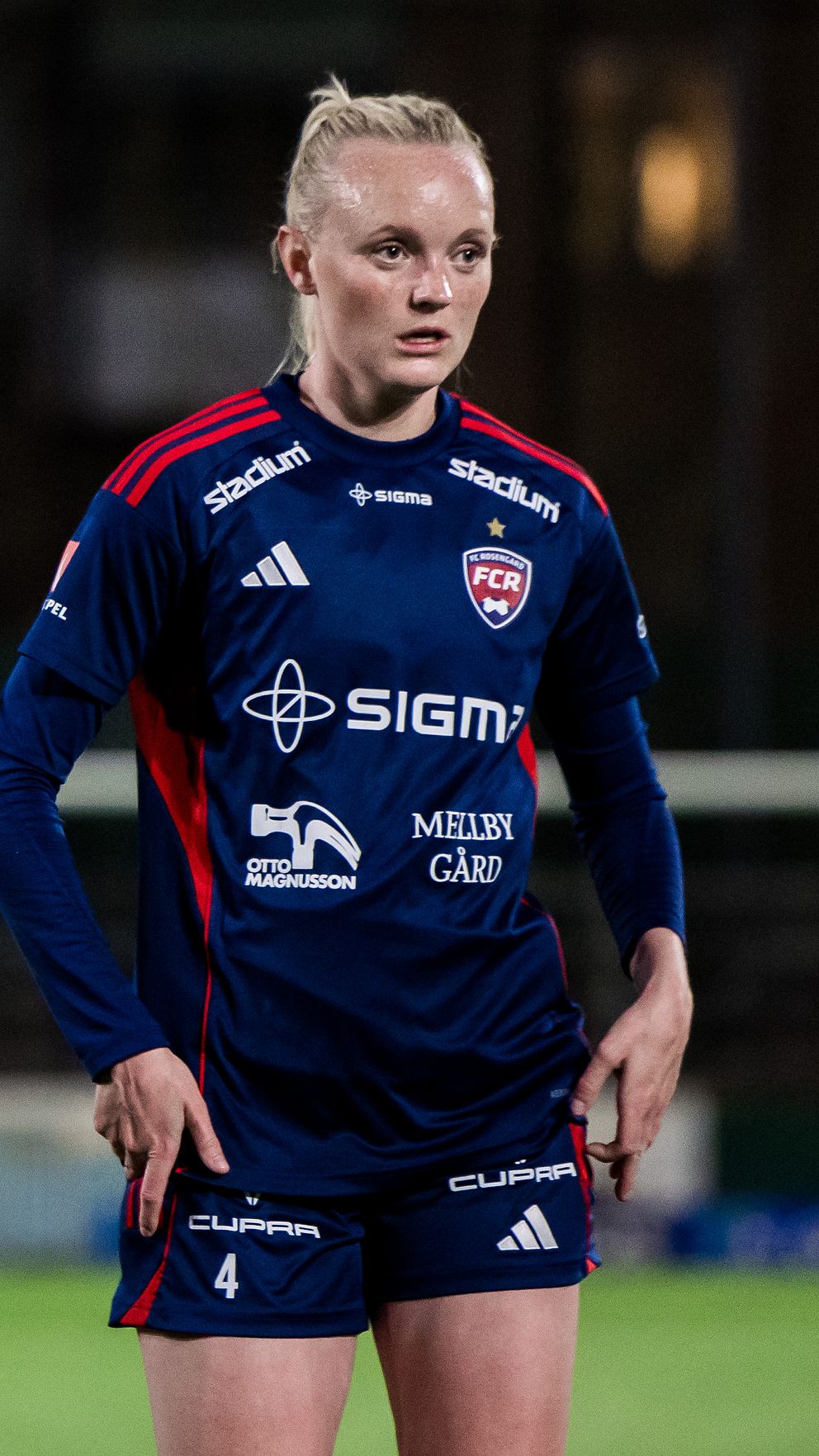 Två fotbollsspelare i blå matchtröjor står tillsammans på planen.