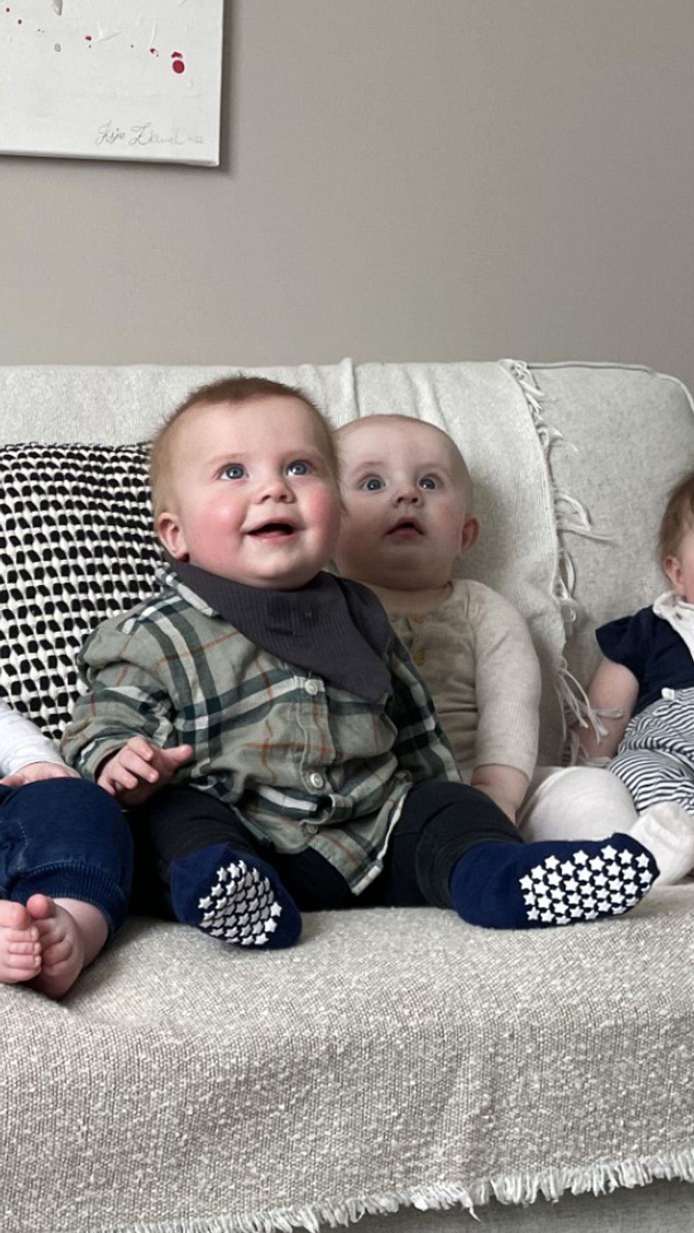 Sex bebisar sitter på rad i en vit soffa.
