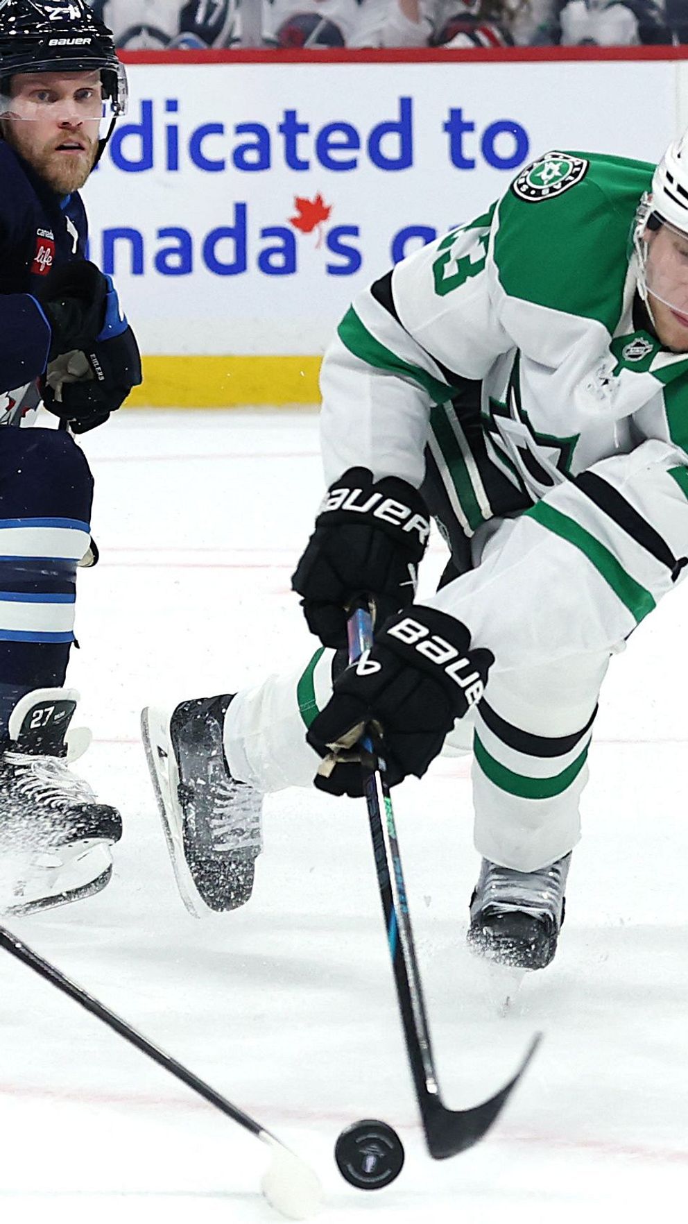 Två Dallas Stars-spelare jagar pucken under en ishockeymatch mot Winnipeg Jets.