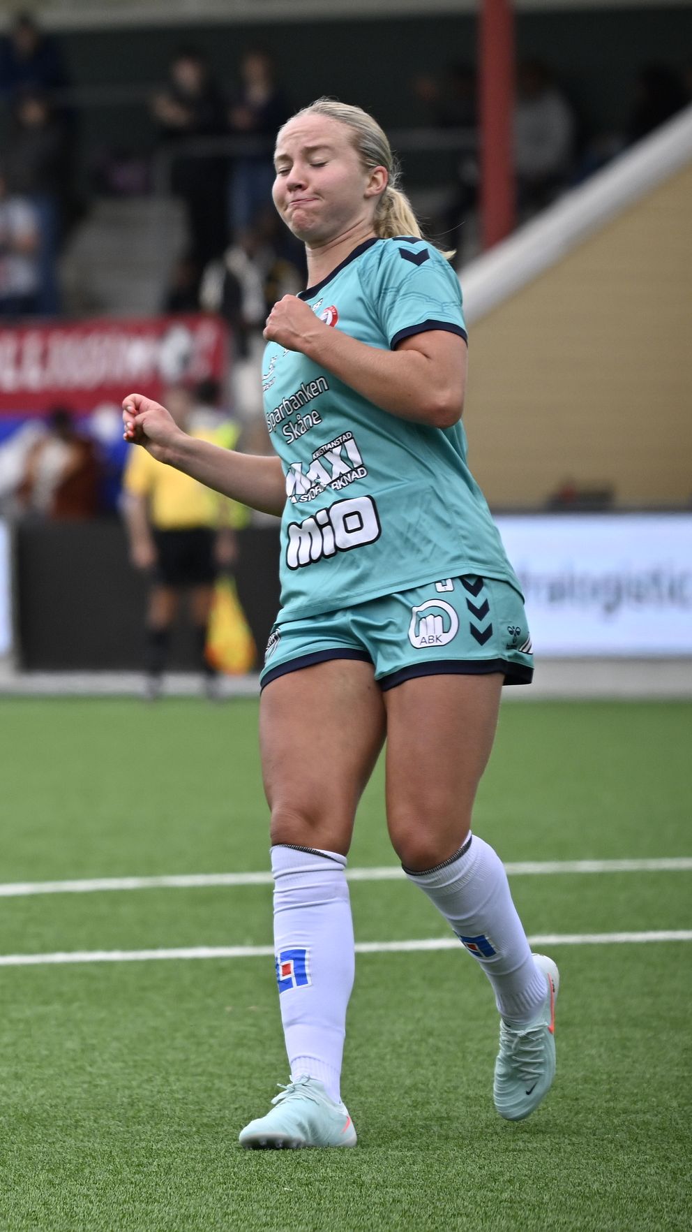 Fotbollsspelare sparkar bollen, motspelare i turkos dräkt ser på under match.