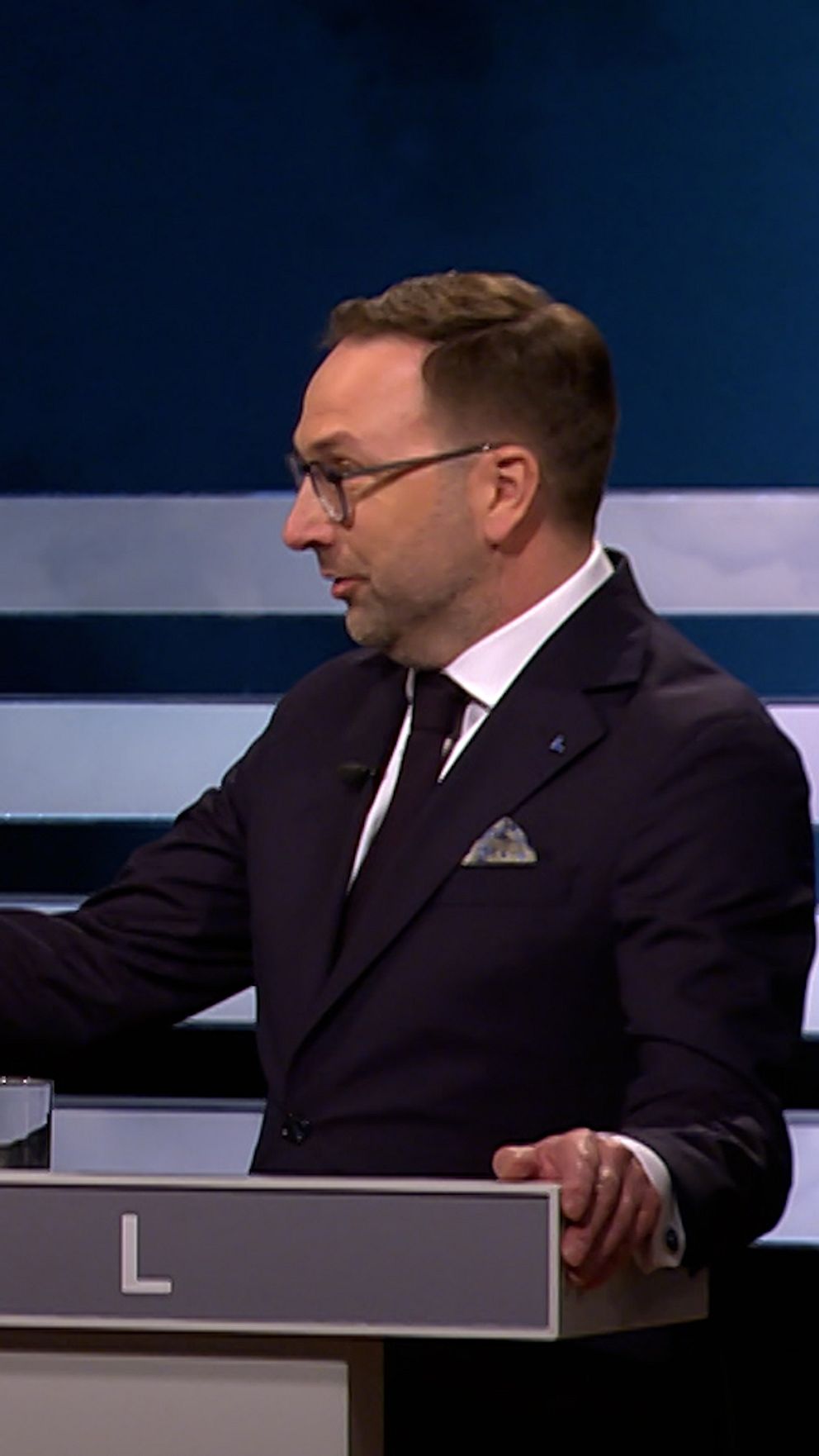 Två politiker i debatt står vid varsin pulpet och gestikulerar mot varandra.